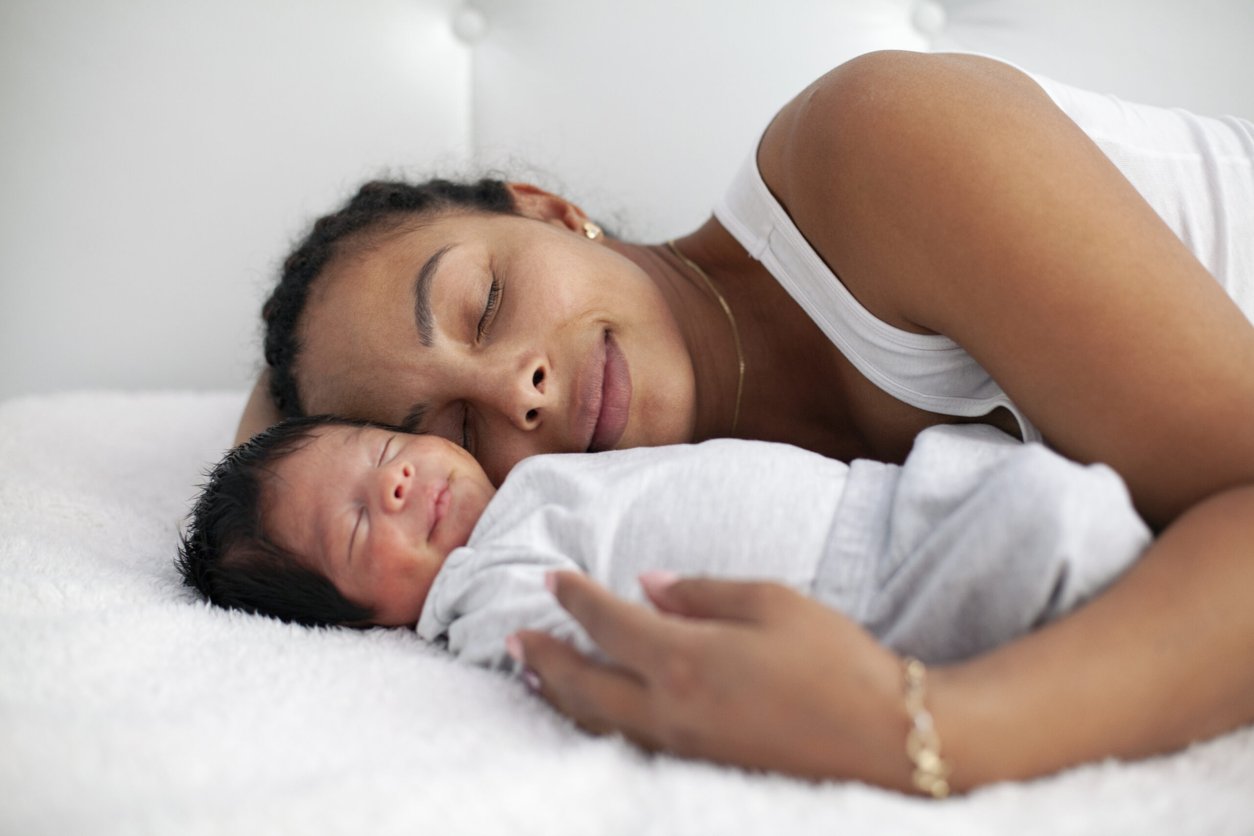 African-American mother having fun with cute baby boy on the bed