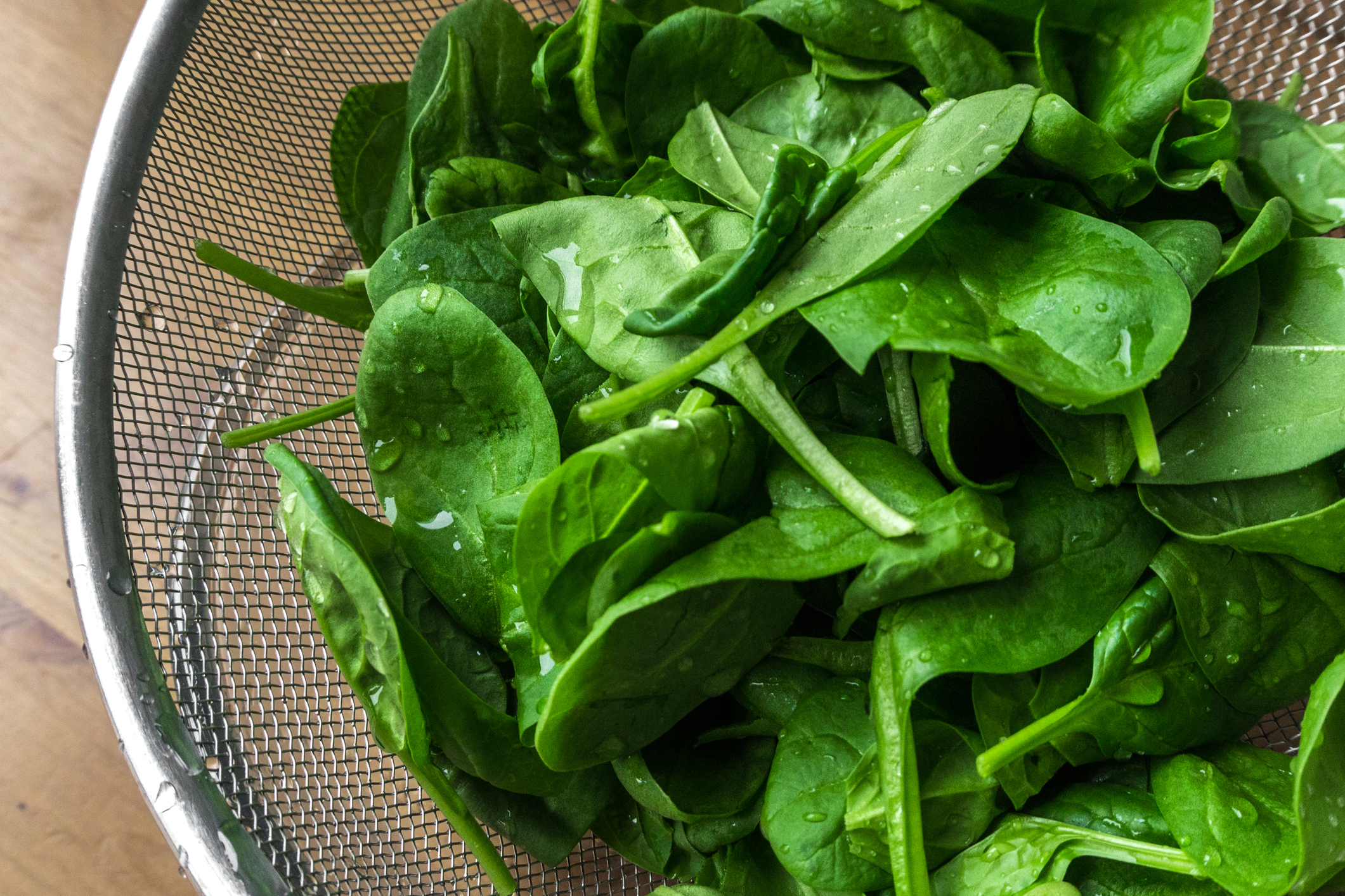 fresh young spinach leaves in a sieve on a table