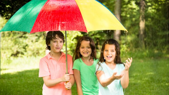 niños cubriendo a niñas con sombrilla