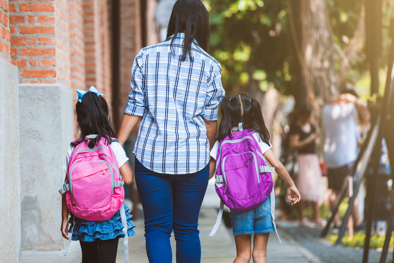 Asian mother and daughter pupil girl with backpack holding hand and going to school together