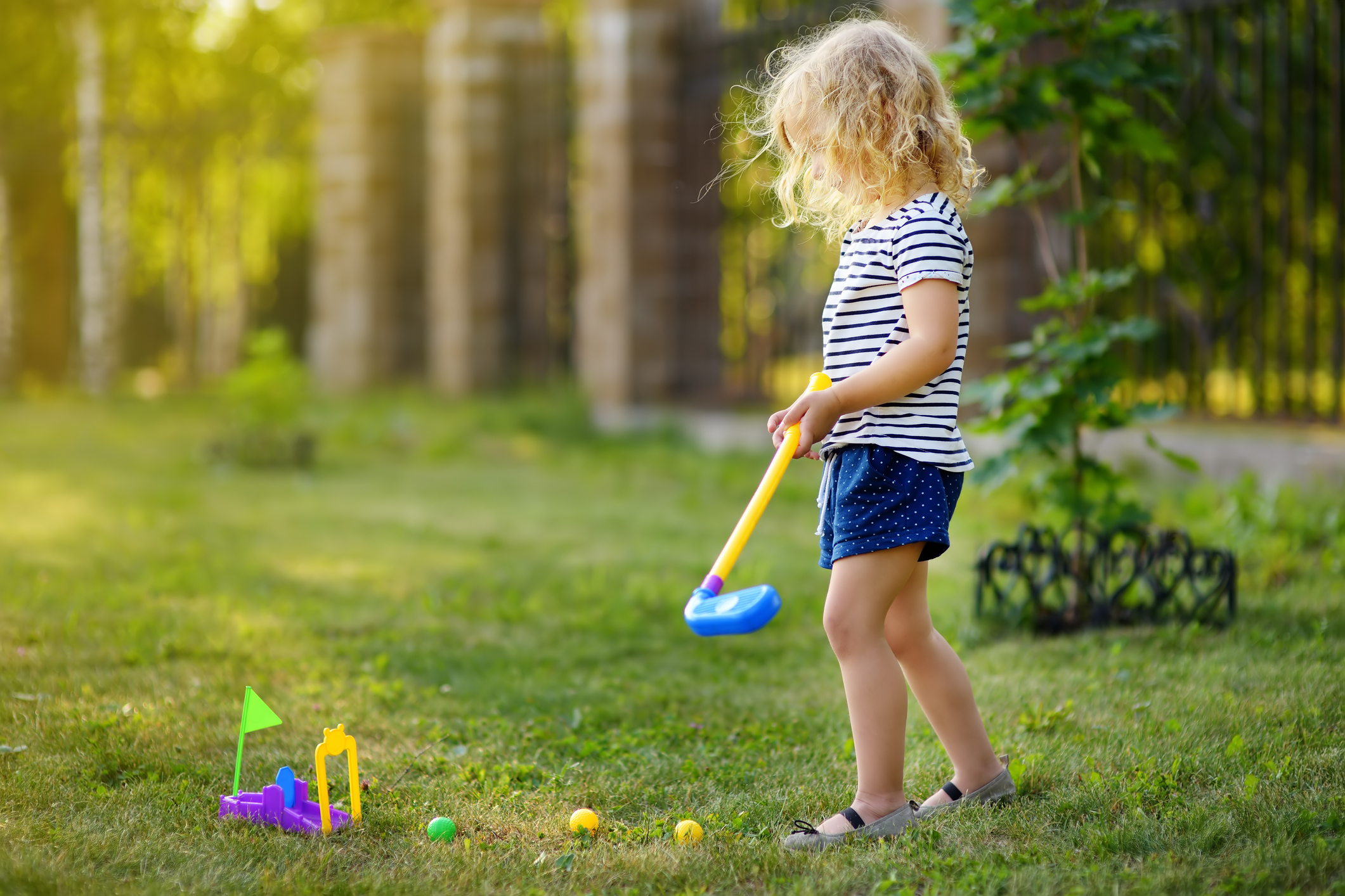 Little girl playing mini golf in spring park. Frustrated child, failure, missed.