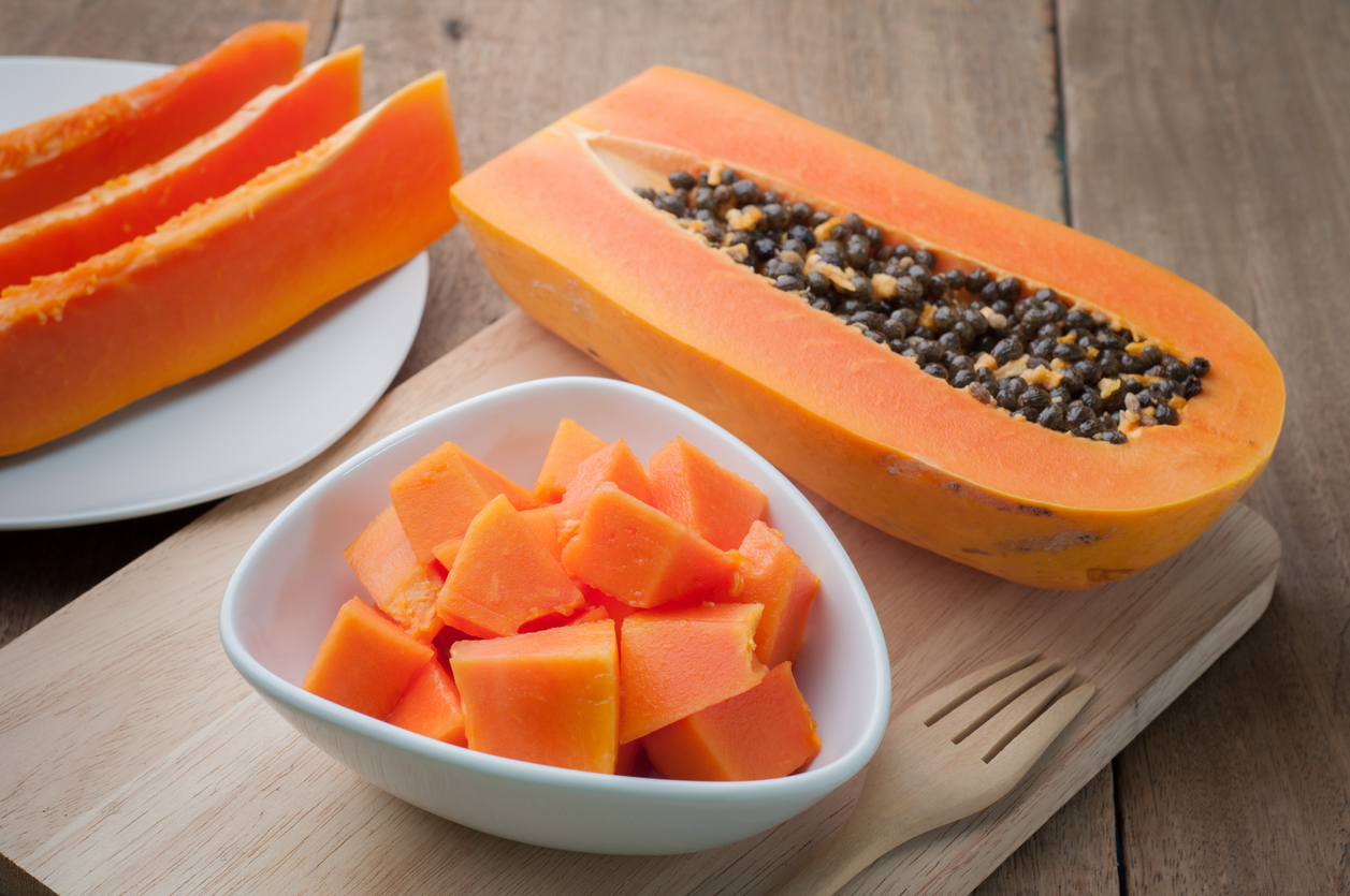 Sliced papaya on white plates and wooden background.