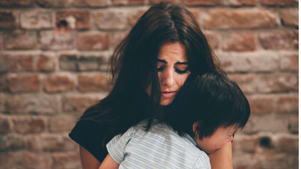 Mujer maltratada abrazando a hijo que llora