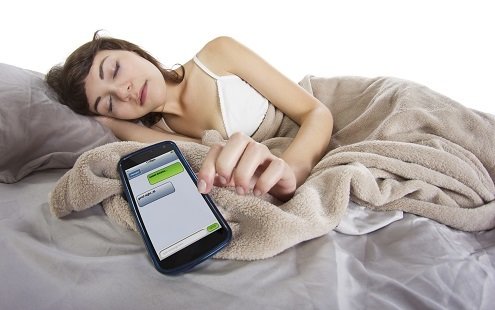 teenager with cell phone in bed