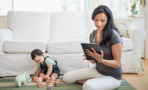 mom on tablet next to baby