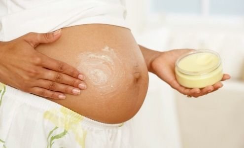 Woman applying stretch mark cream to baby bump