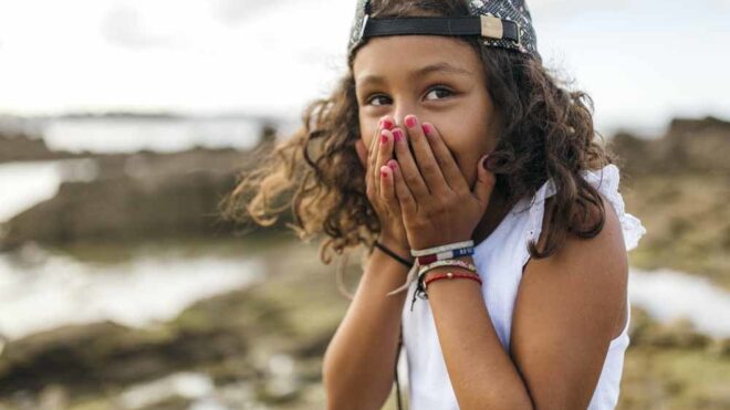 child with hands on mouth