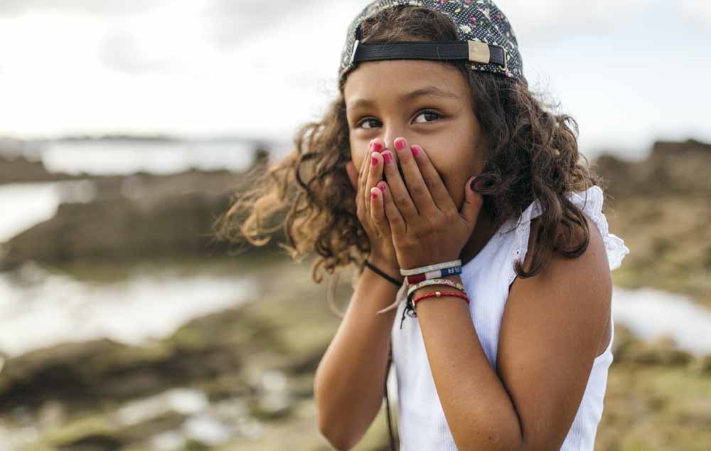 child with hands on mouth