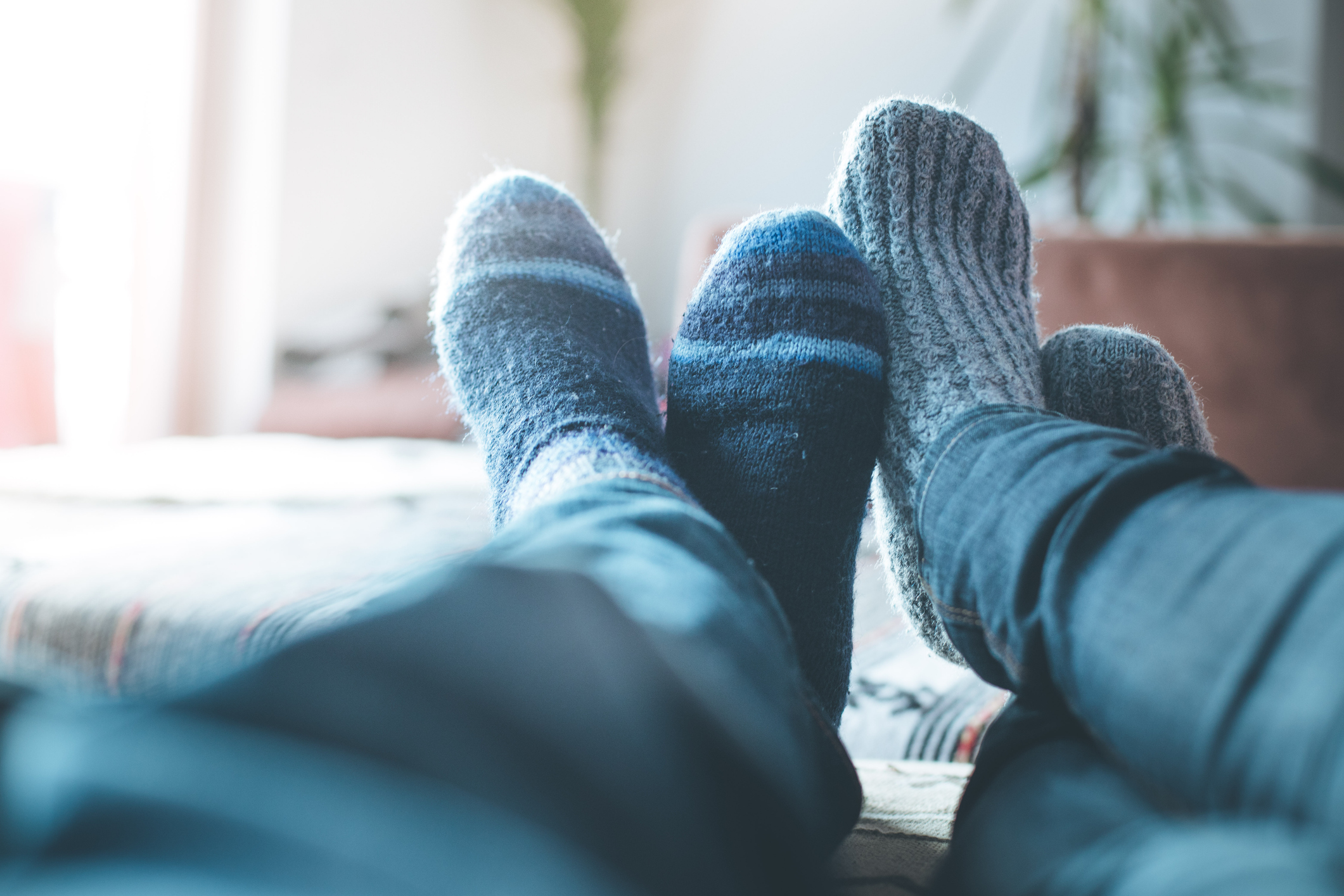 Cosy relaxing in the wintertime at home: Couple with woollen socks is lying on the couch