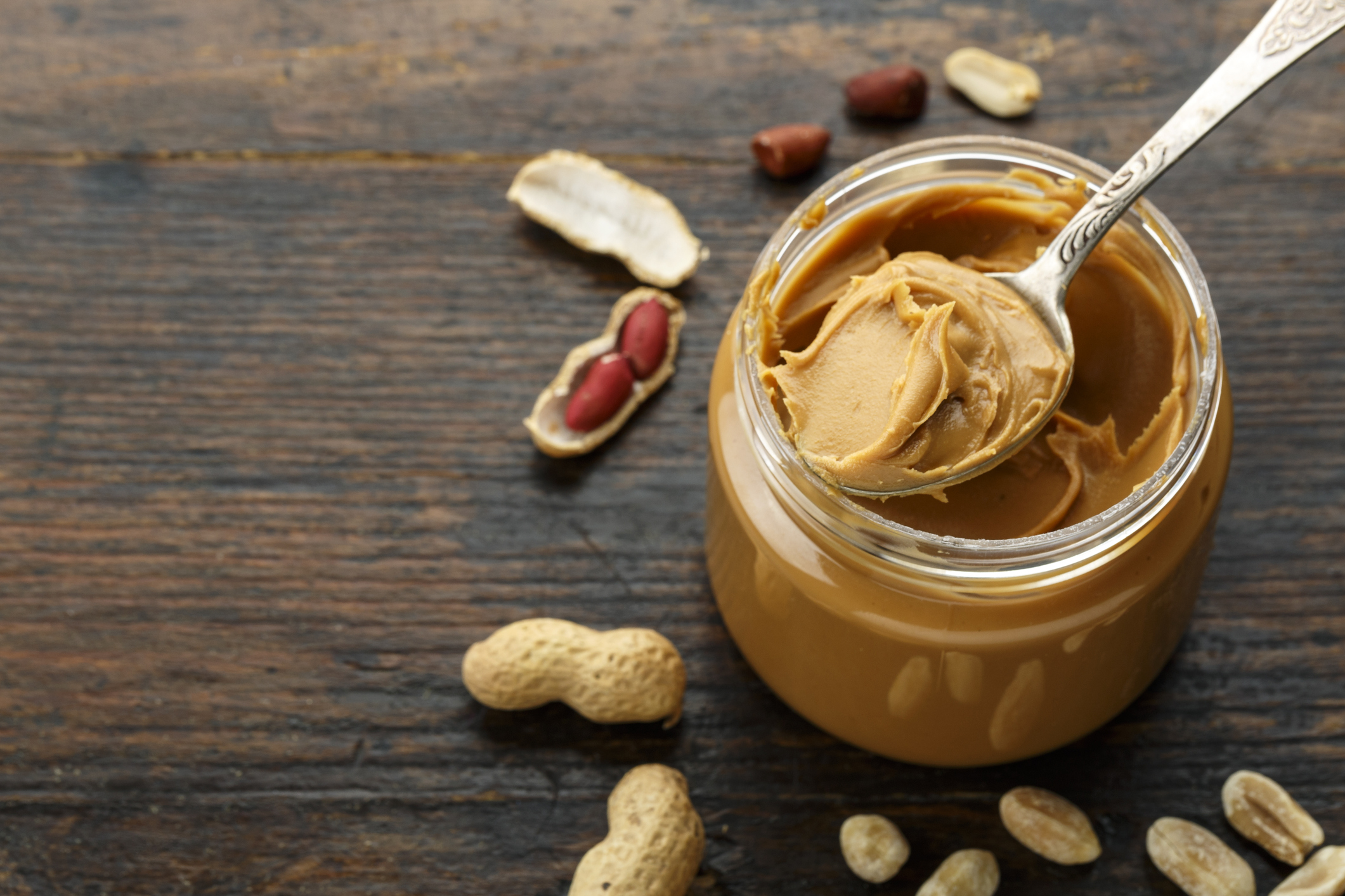 peanut paste in an open jar and peanuts