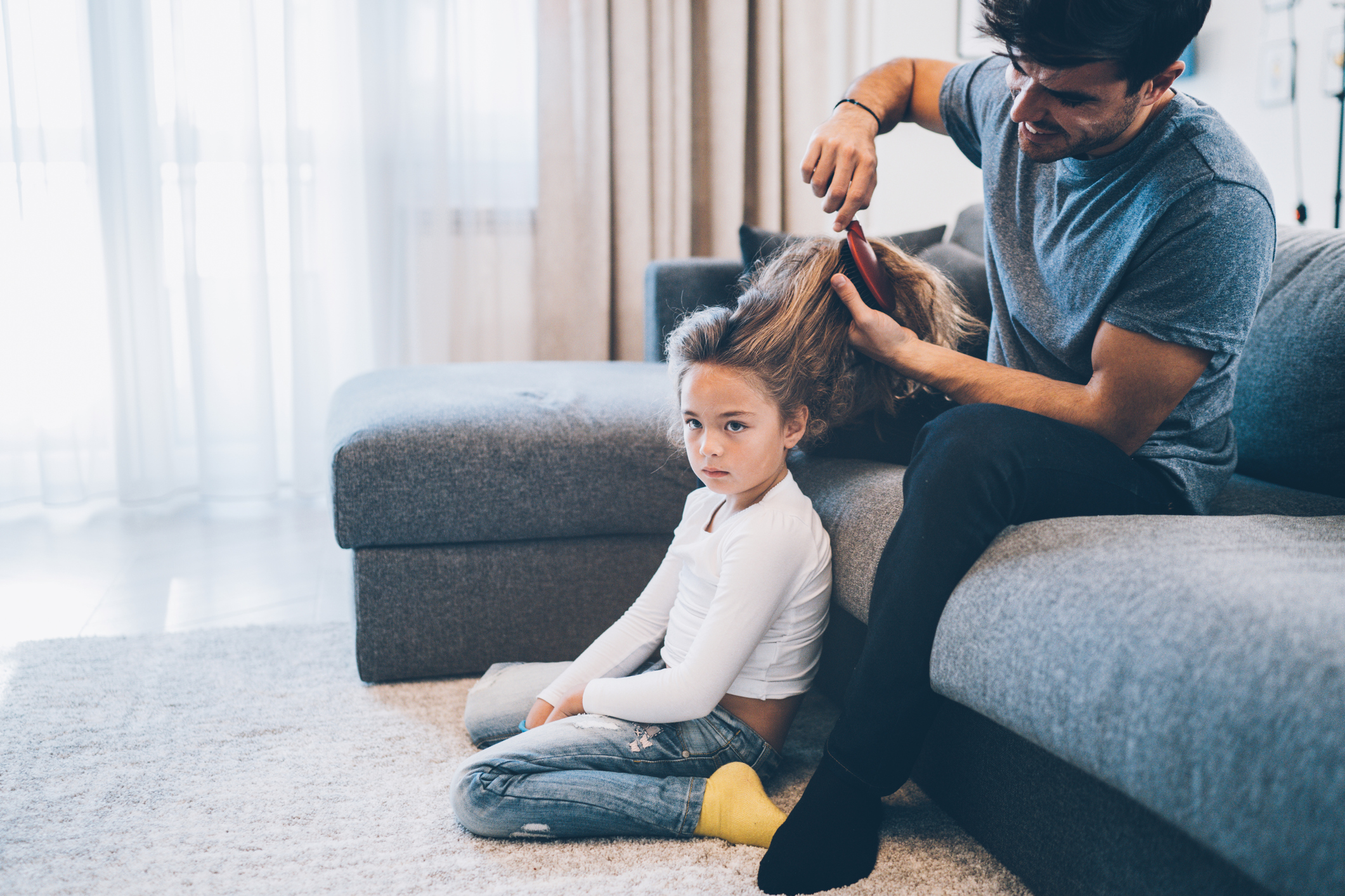 Handsome father brushing hair of daughter