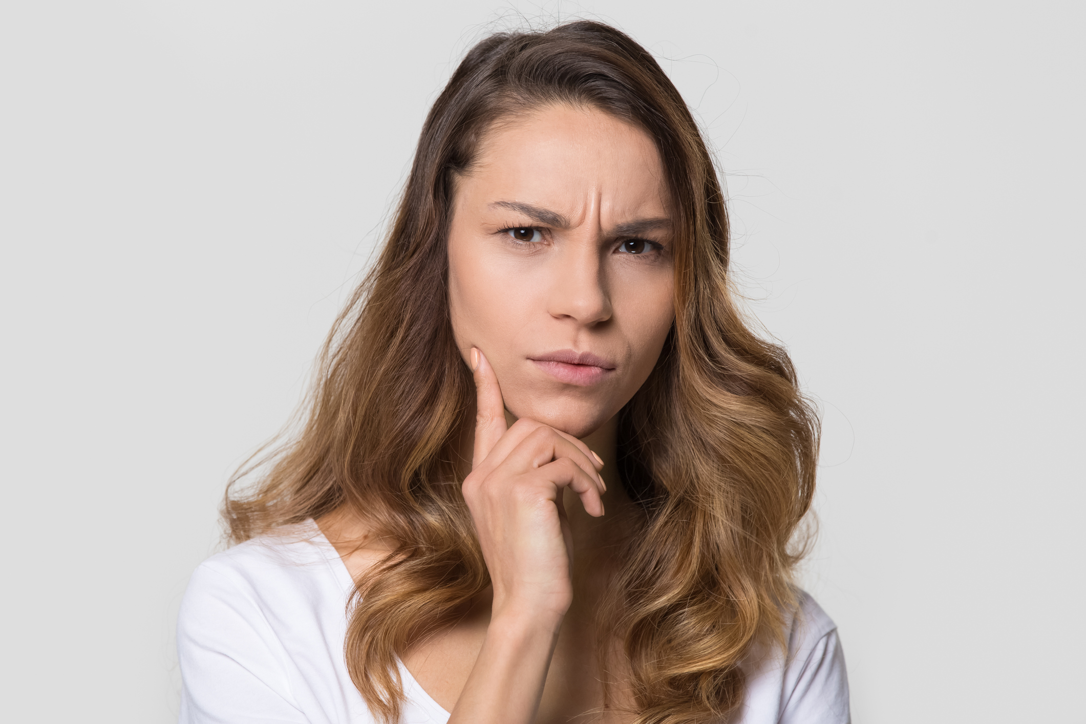 Puzzled perplexed woman with frowning face isolated on studio wall