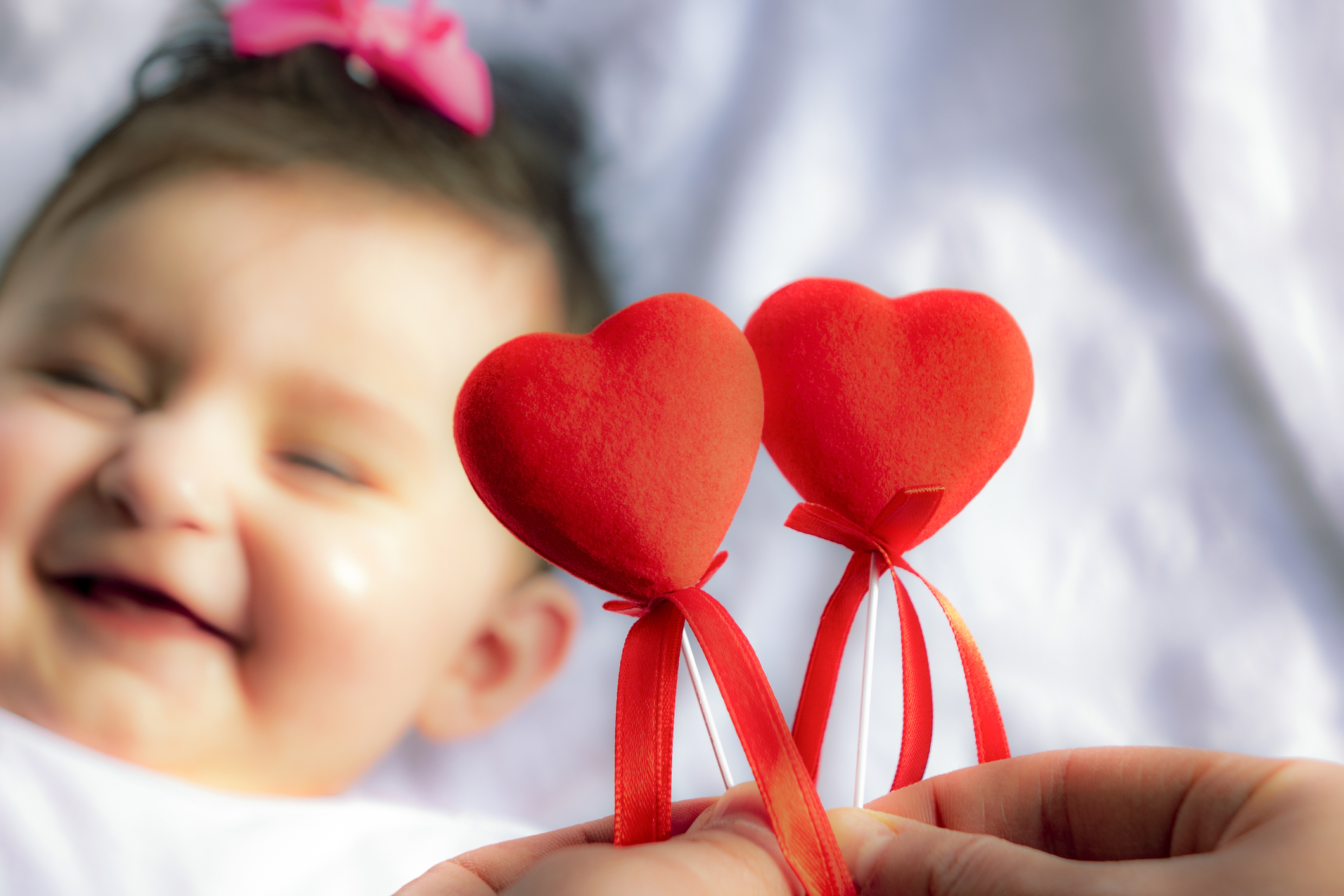 Valentine's day picture of smiling baby on a hearts that says be mine on white fabric surface