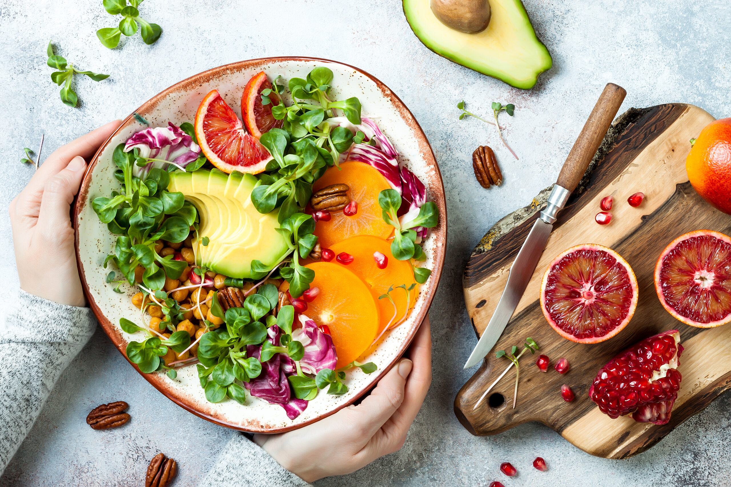 Vegan, detox Buddha bowl with turmeric roasted  chickpeas, greens, avocado, persimmon, blood orange, nuts and pomegranate. Top view, flat lay