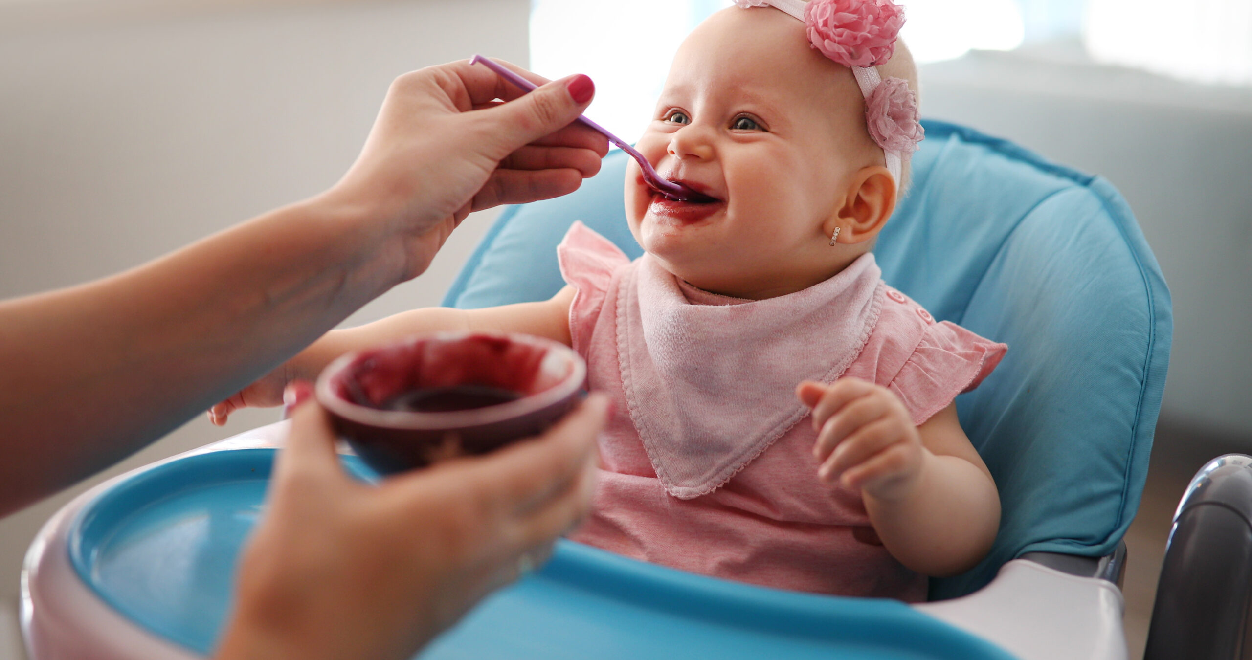 Pleasant young woman feeding a cute baby