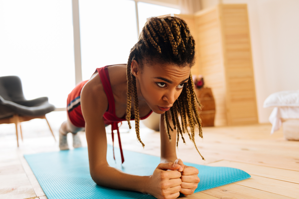 Dark-eyed woman feeling exhausted while finishing workout with plank