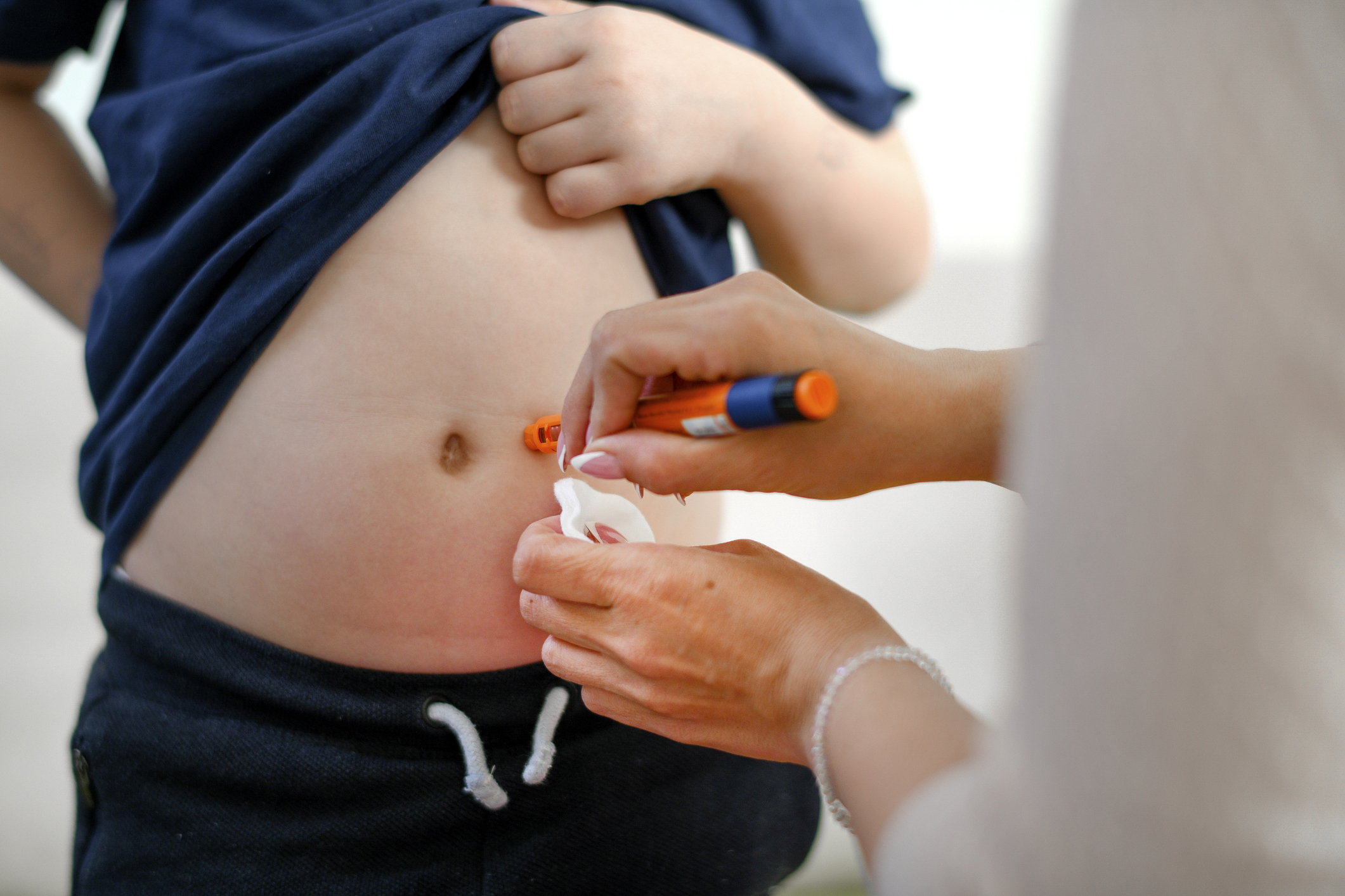 Boy taking an insulin shot at stomach