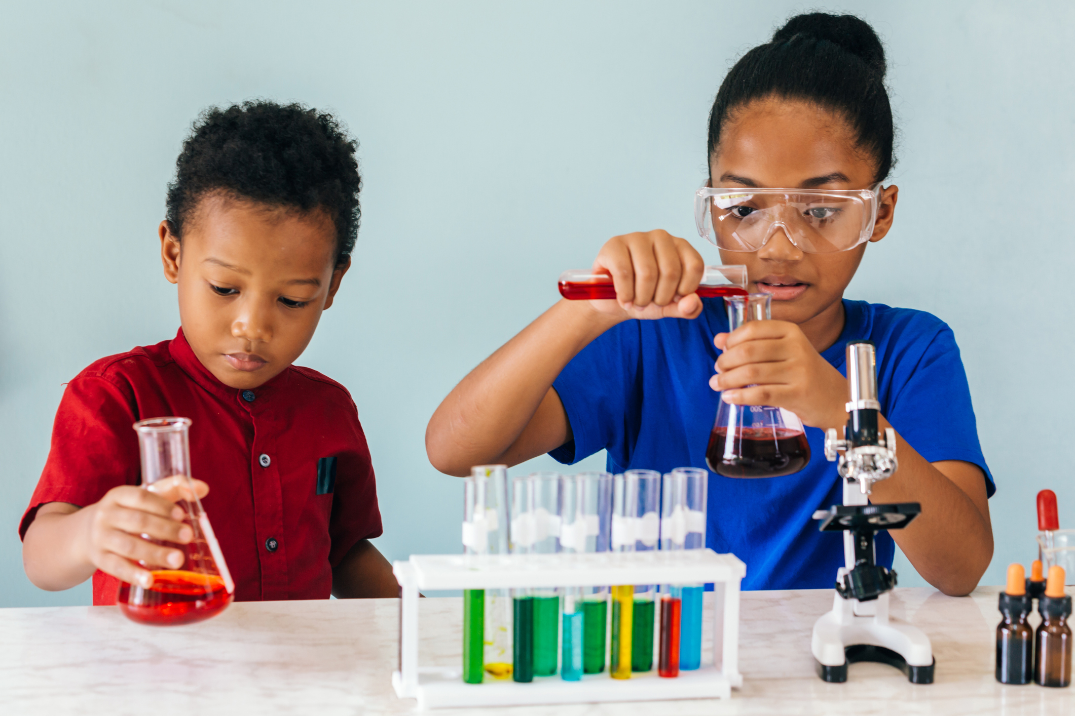 Two African American mixed kids testing chemistry lab experiment