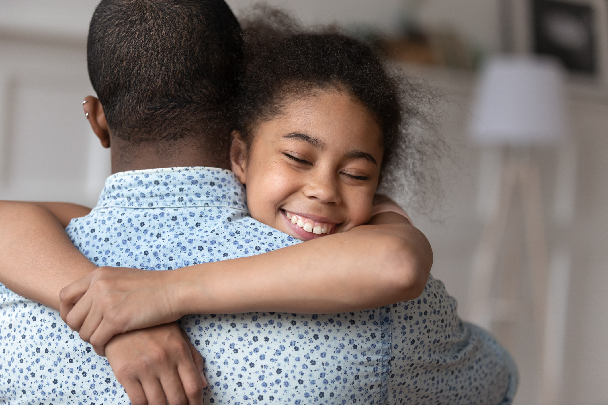 Smiling cute african american child daughter hugging dad feeling love