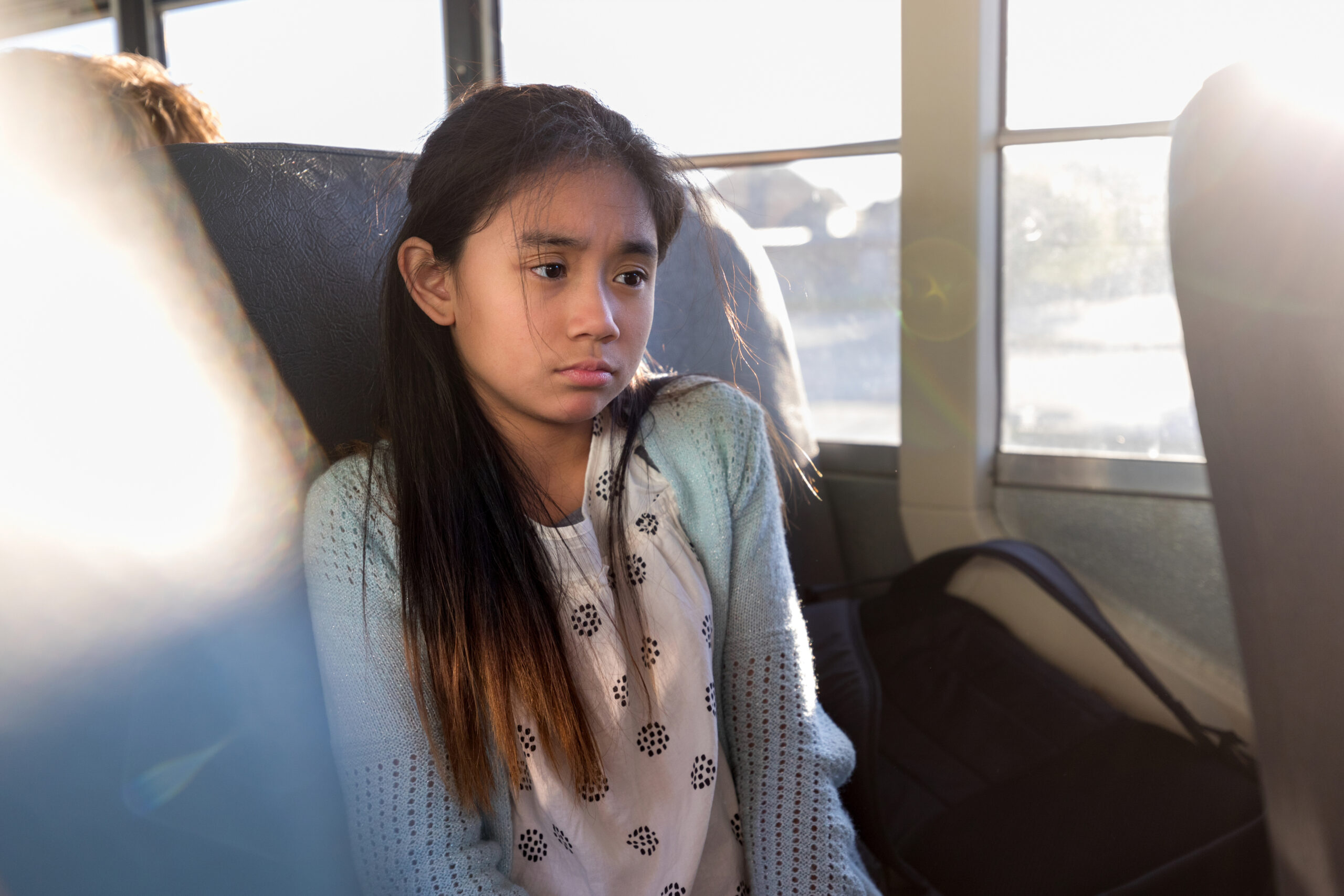 On bus, young girl is sad after a hard day