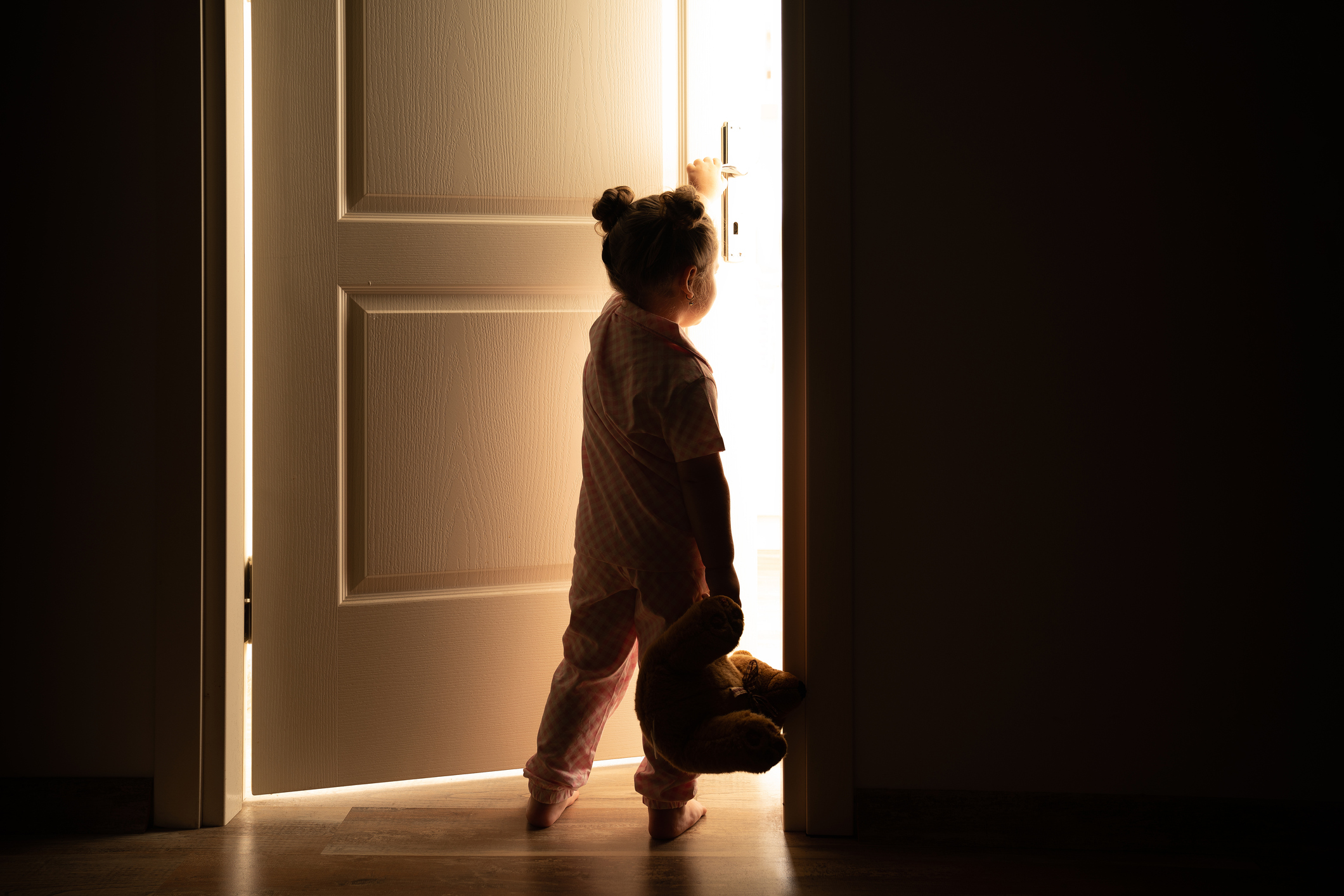 Little girl opens the door to the light in darkness