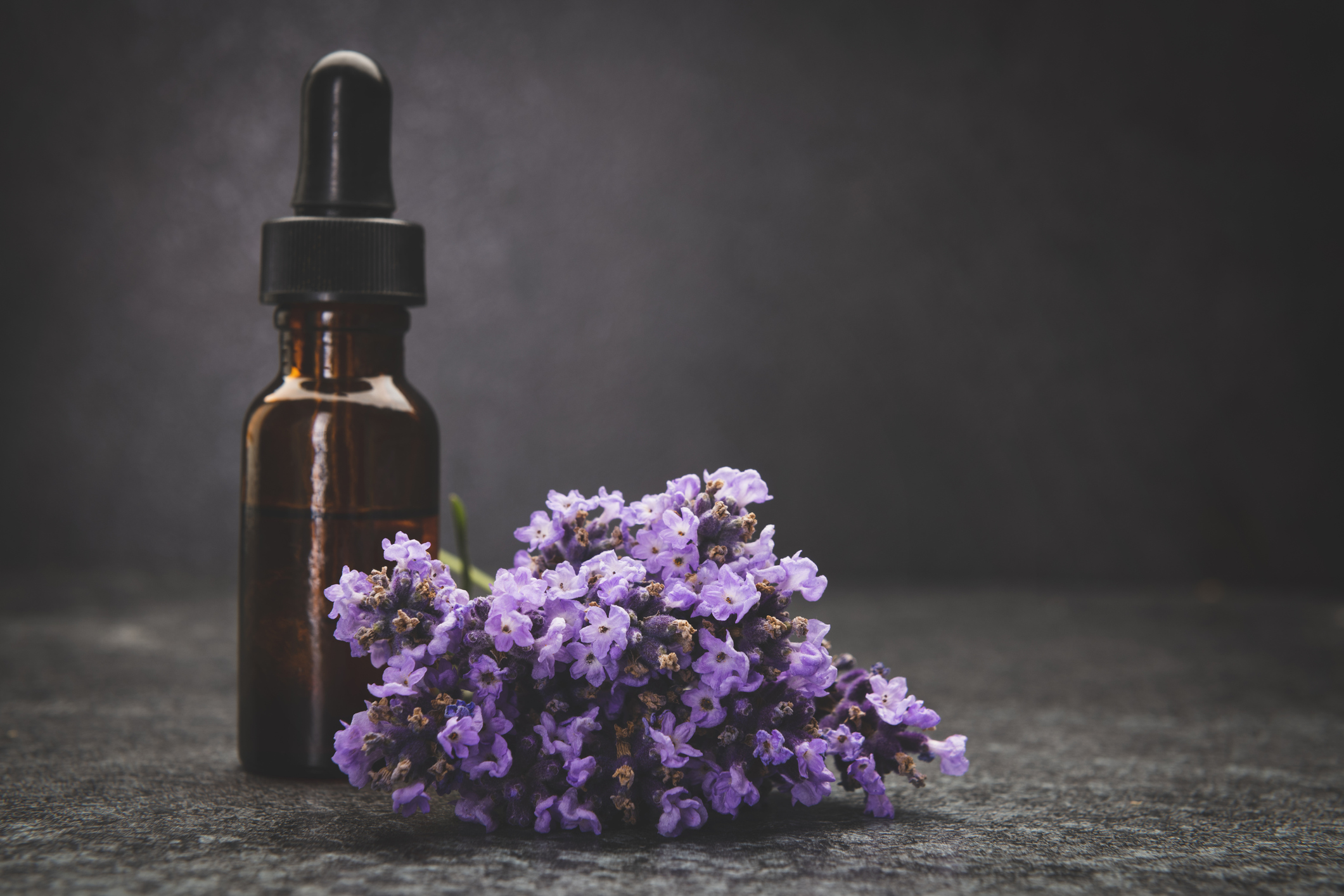 A bottle of lavender essential oil with fresh lavender twigs