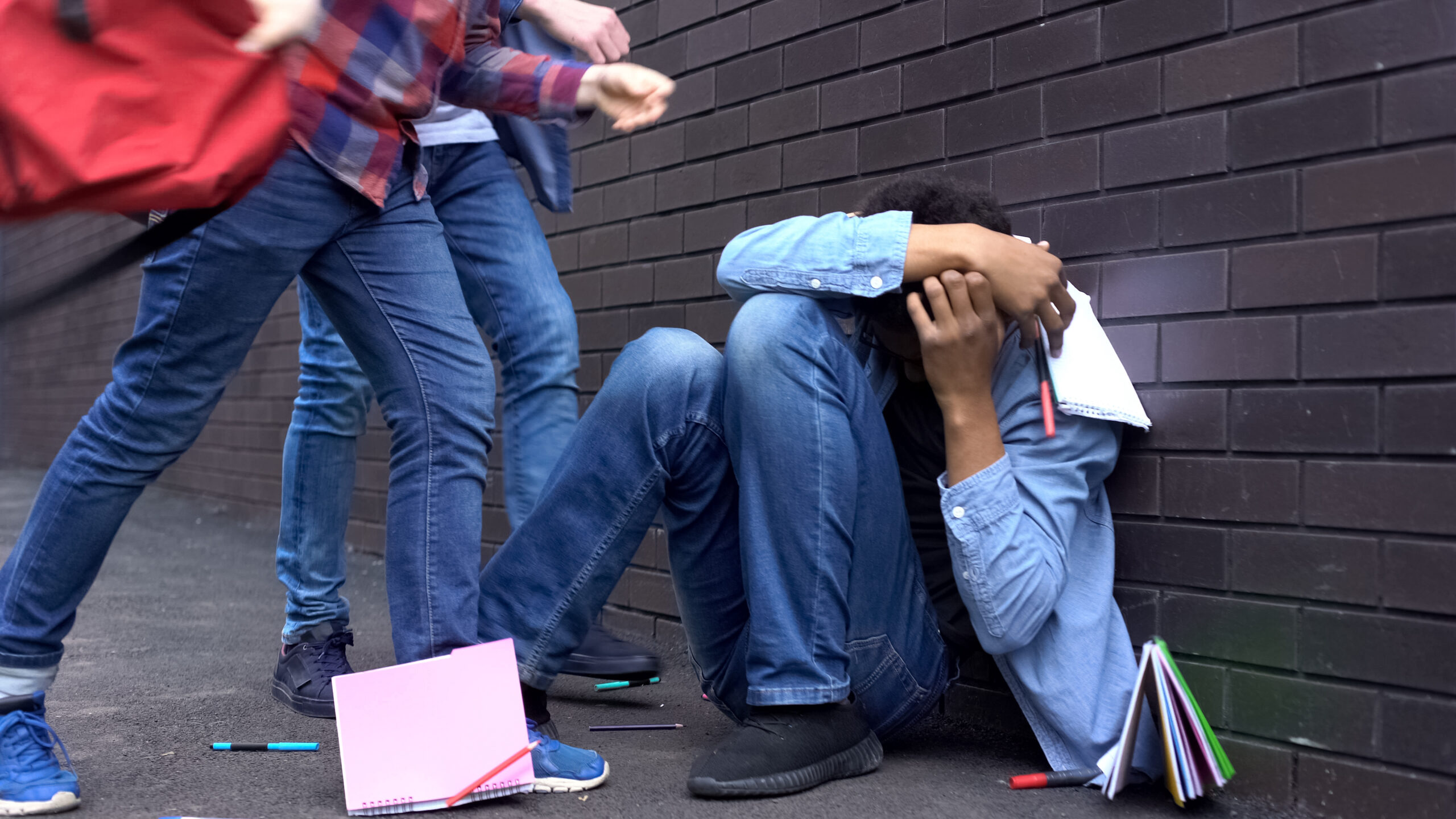 Cruel teenagers scattering classbooks of afro-american boy, school bullying