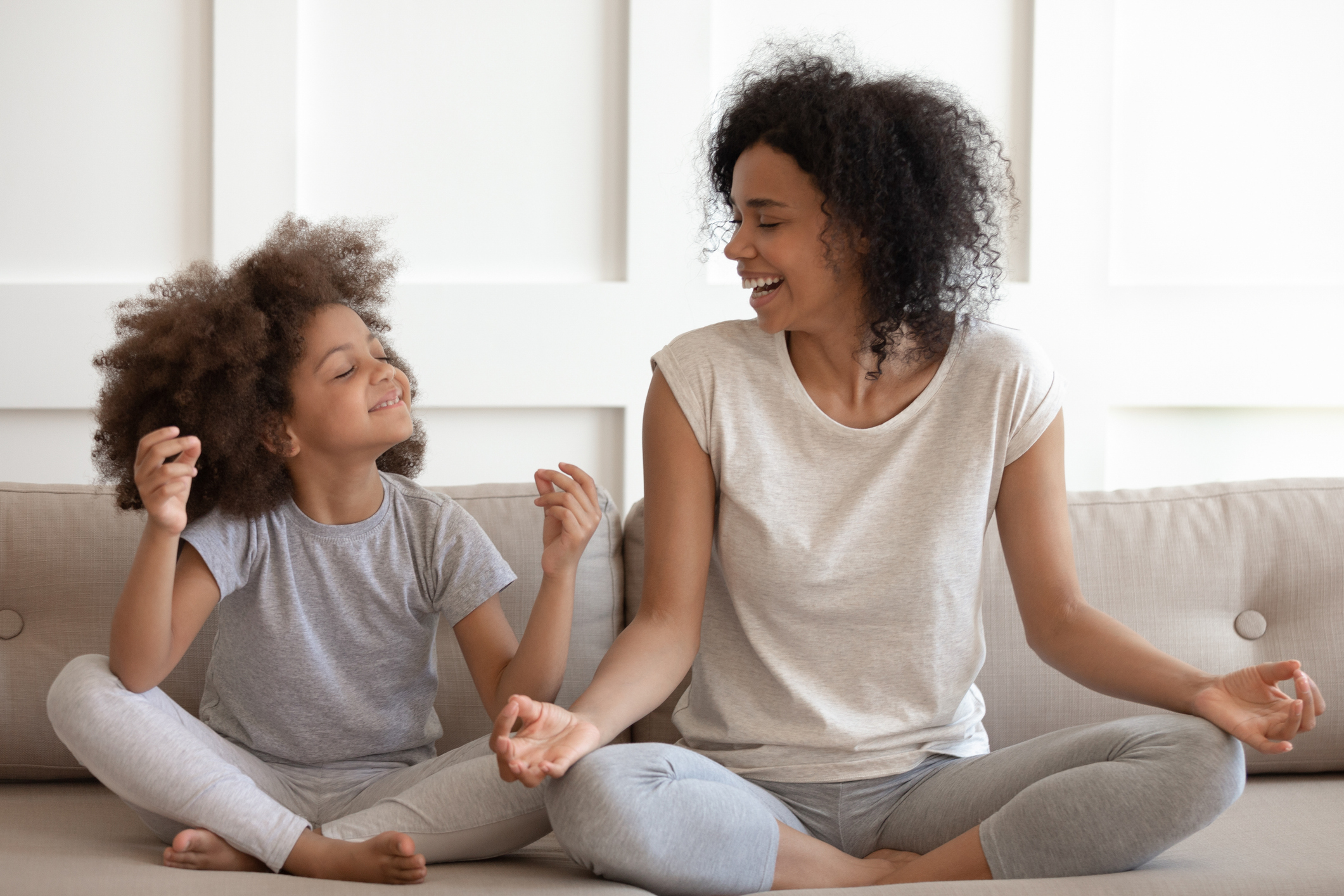 Excited african american woman practicing yoga with little daughter.