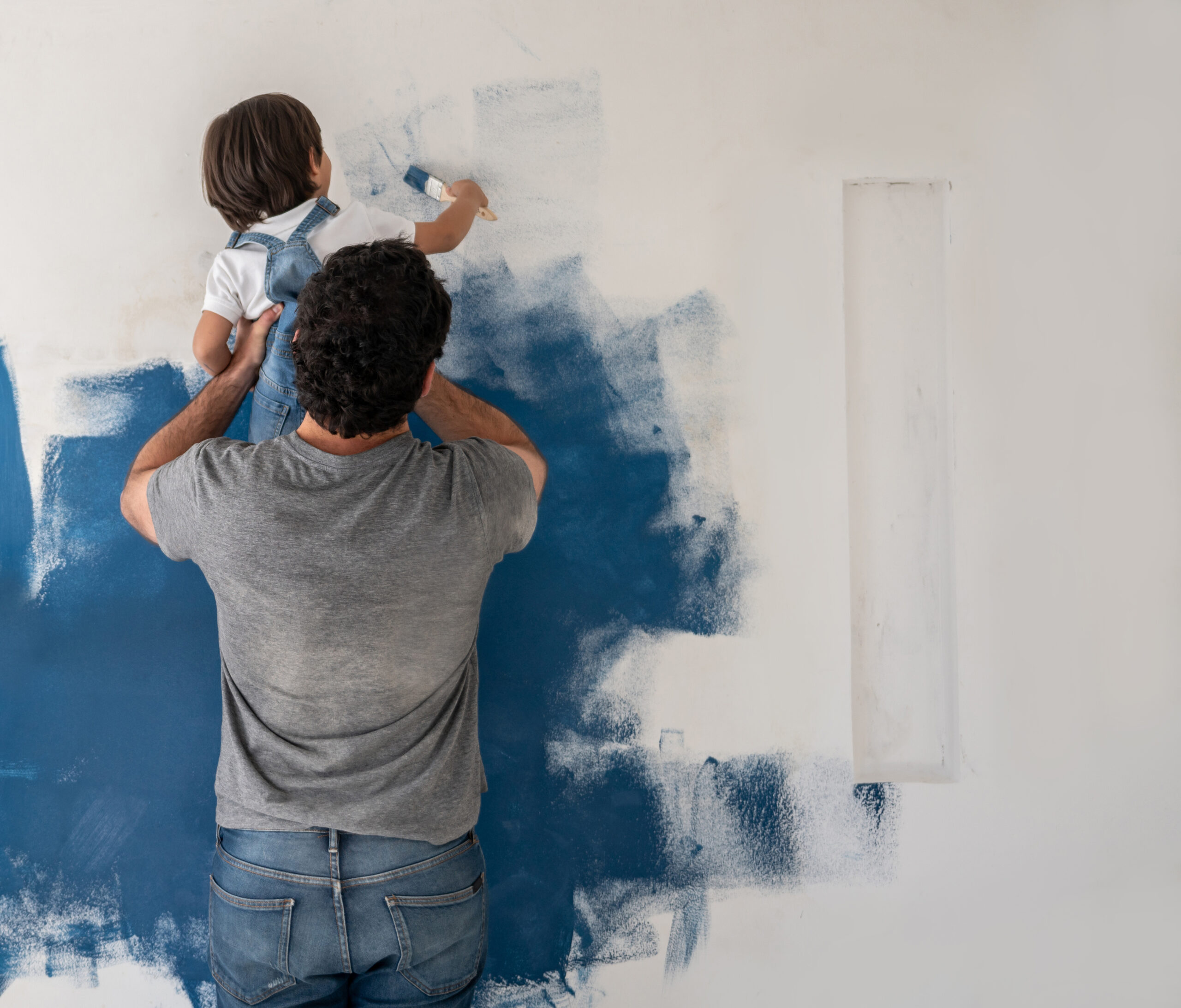 Boy helping his father painting the house