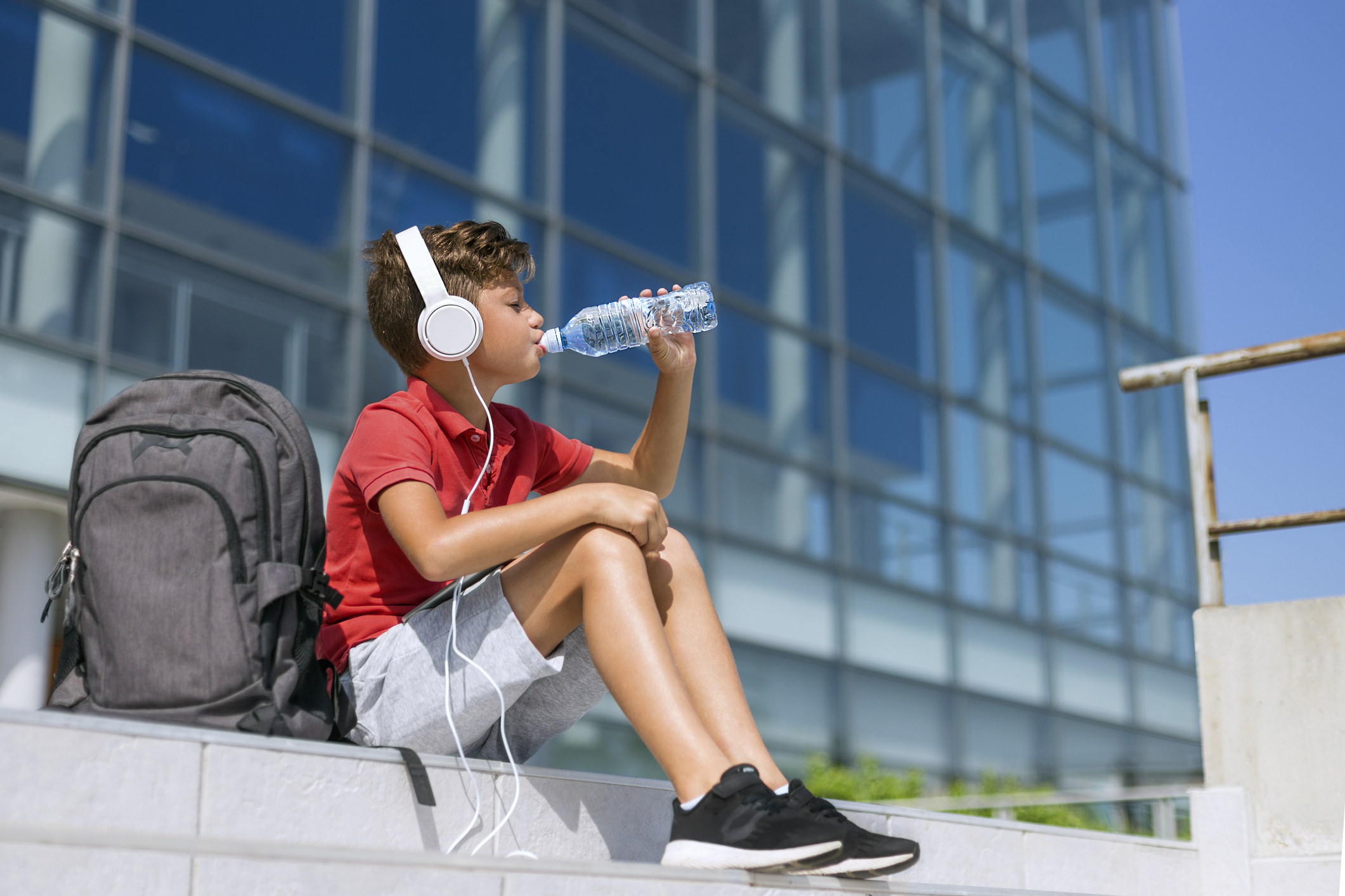 Boy with headphones drinking water