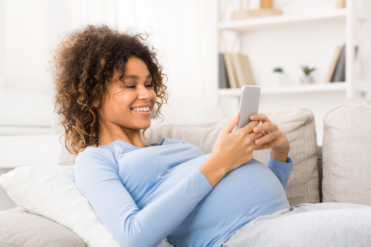 Happy pregnant woman surfing the net on smartphone