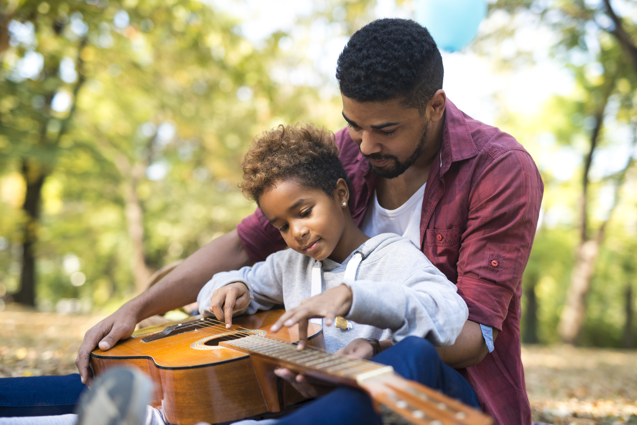 Padre enseñándole a tocar guitarra a su hija