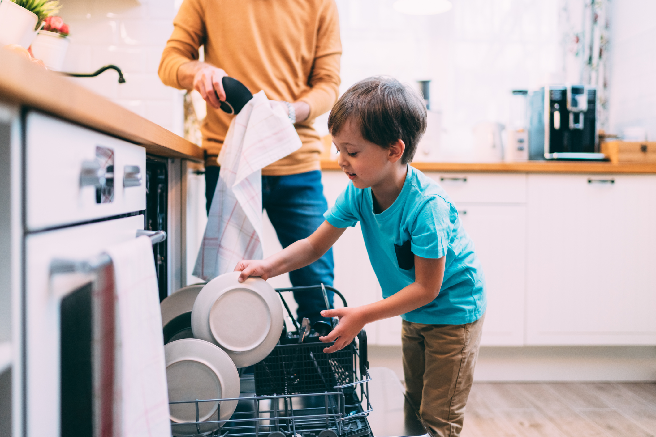 Son helping father with the dishwasher. Chores concept