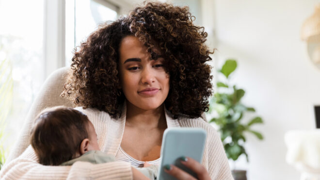 Mamá usando celular mientras carga a su bebé