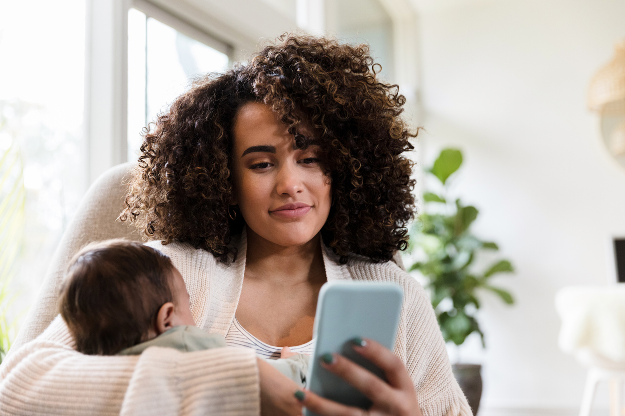 Mamá usando celular mientras carga a su bebé