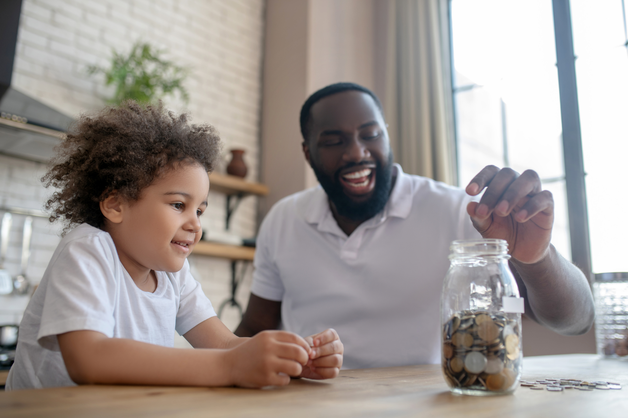 Dark-skinned bearded man putting coins into the moneybank