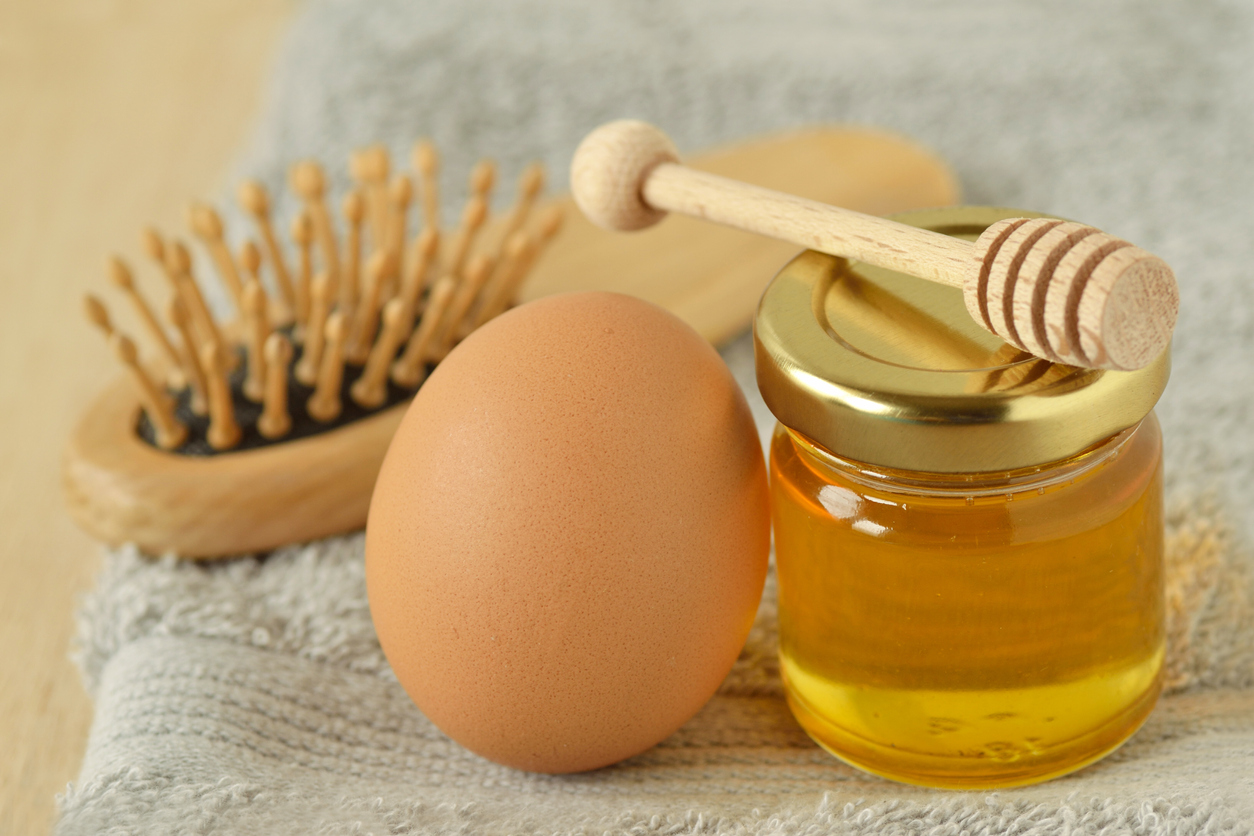 Egg and honey with hair brush on grey towel - Homemade hair mask ingredients