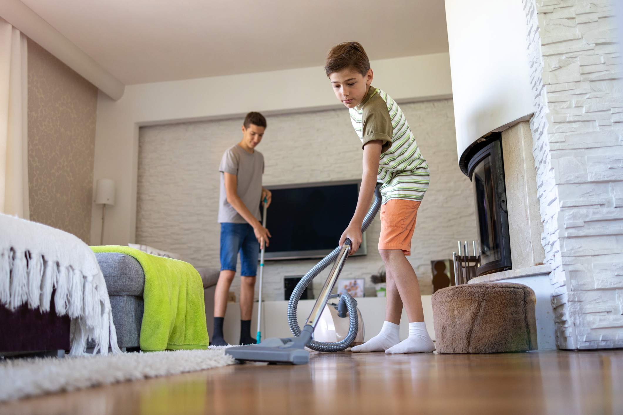 Brothers vacuuming floor at home