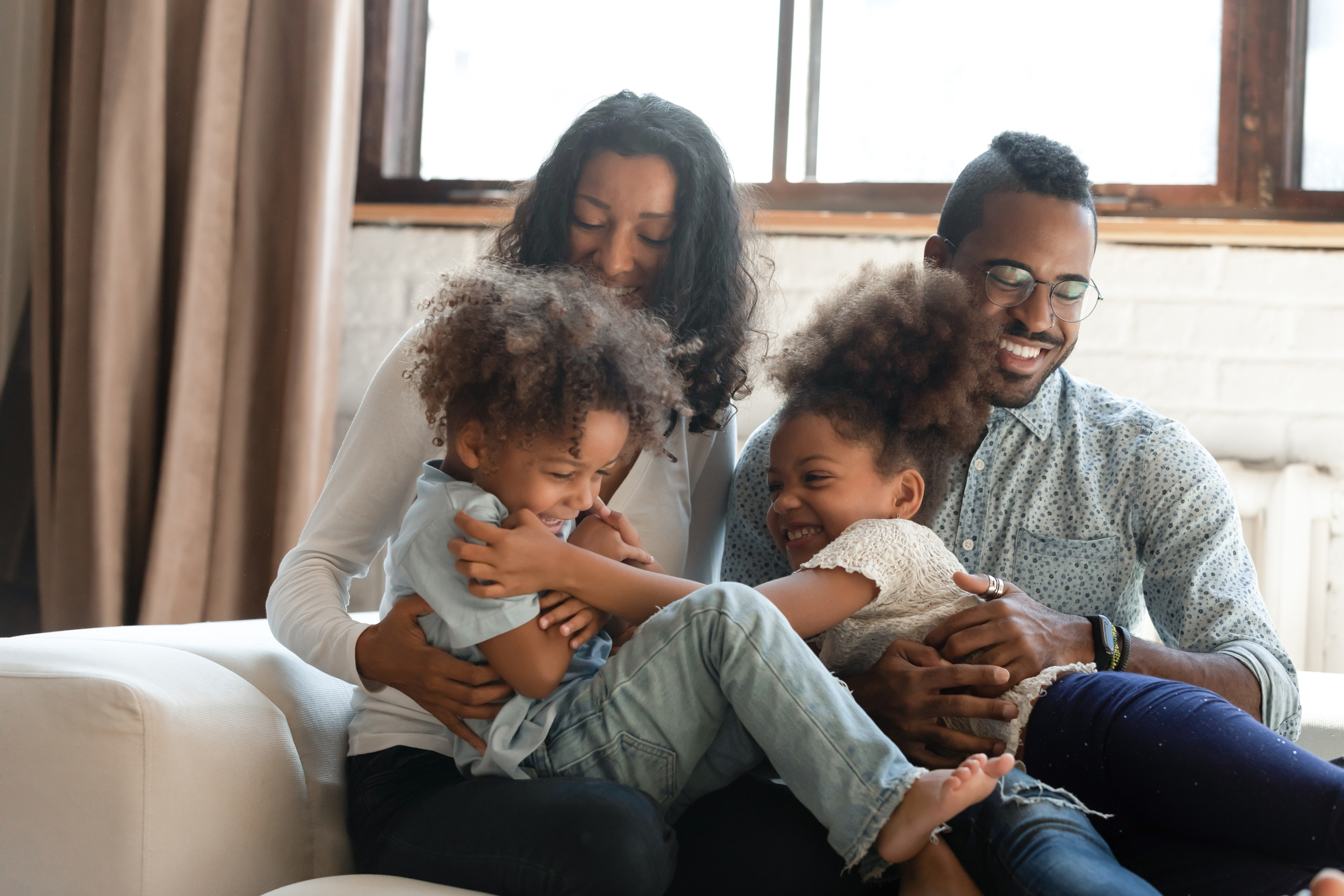 Playful biracial parents play tickle little kids