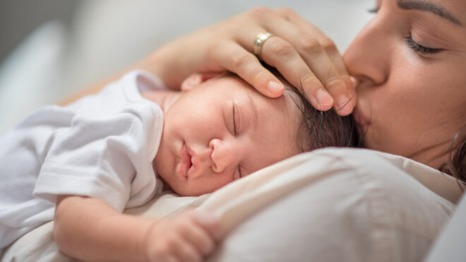 Mamá cargando y besando a bebé mientras duerme