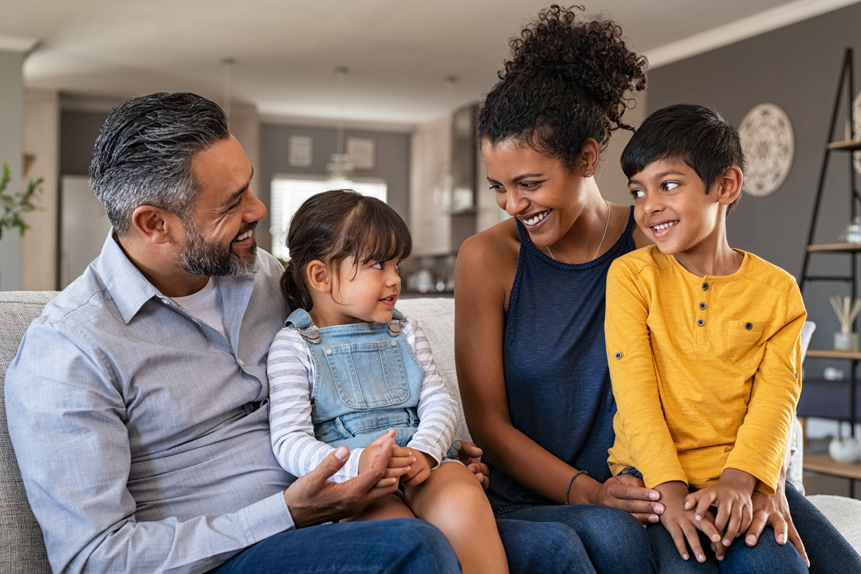 Happy ethnic family with two kids on couch