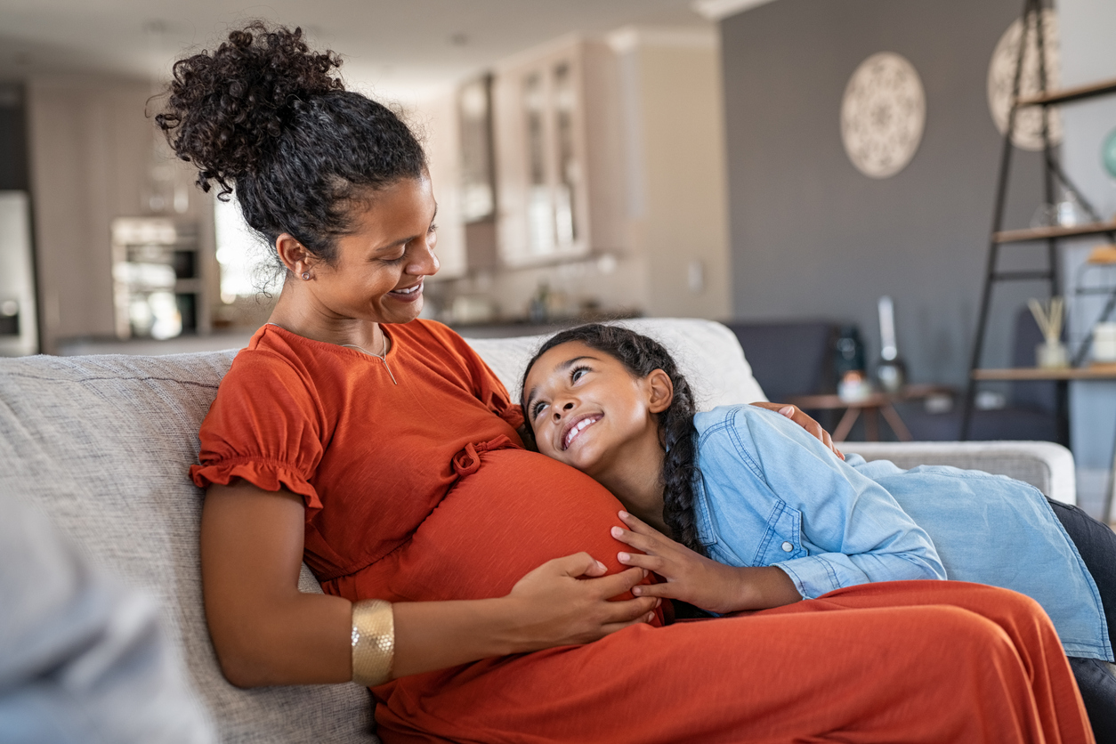 Happy lovely daughter hugging pregnant mother