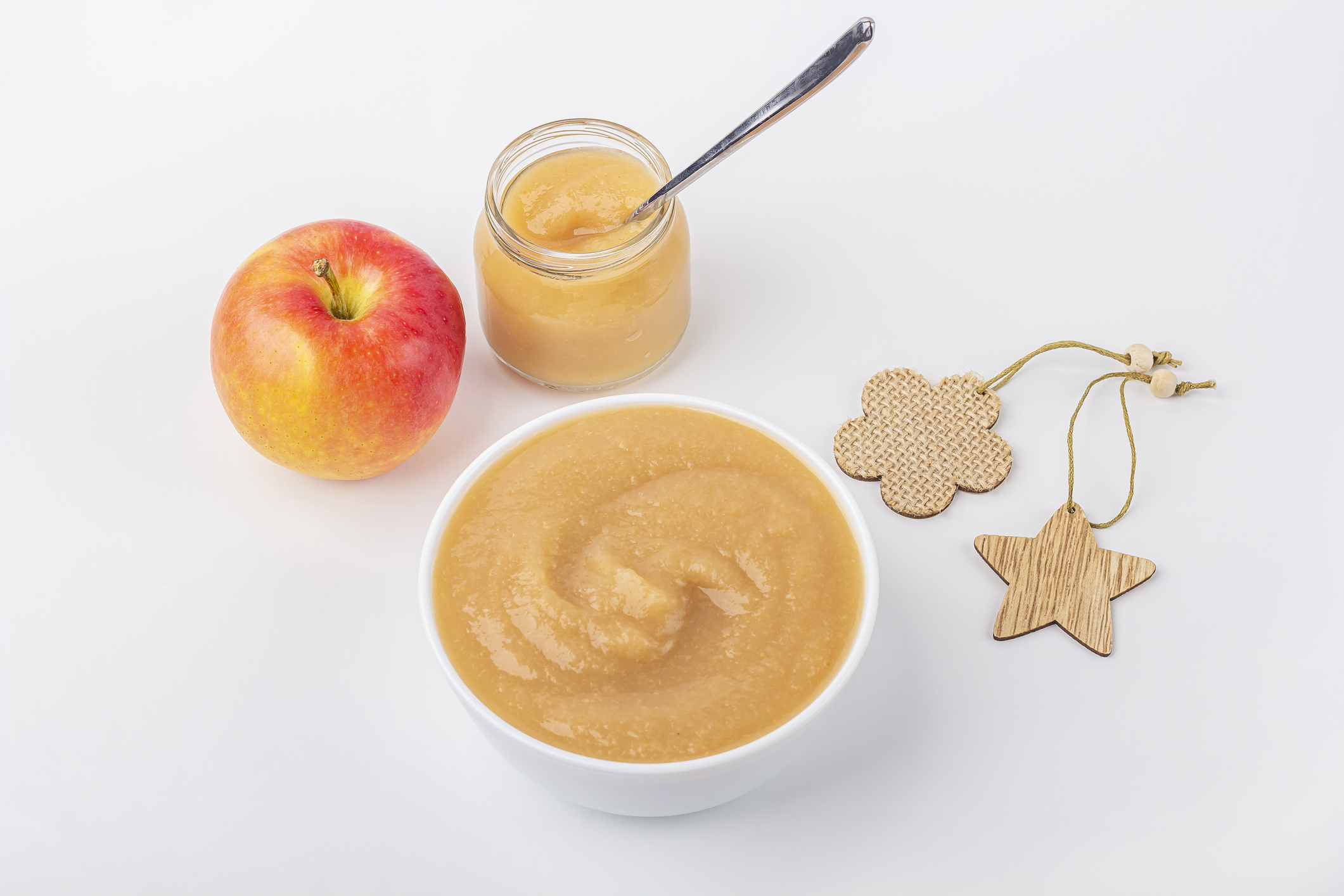 Fresh homemade applesauce in white bowl and jar with fruit puree on white table. The concept of proper nutrition and healthy eating. Organic and vegetarian food. Baby food. Copy space for text