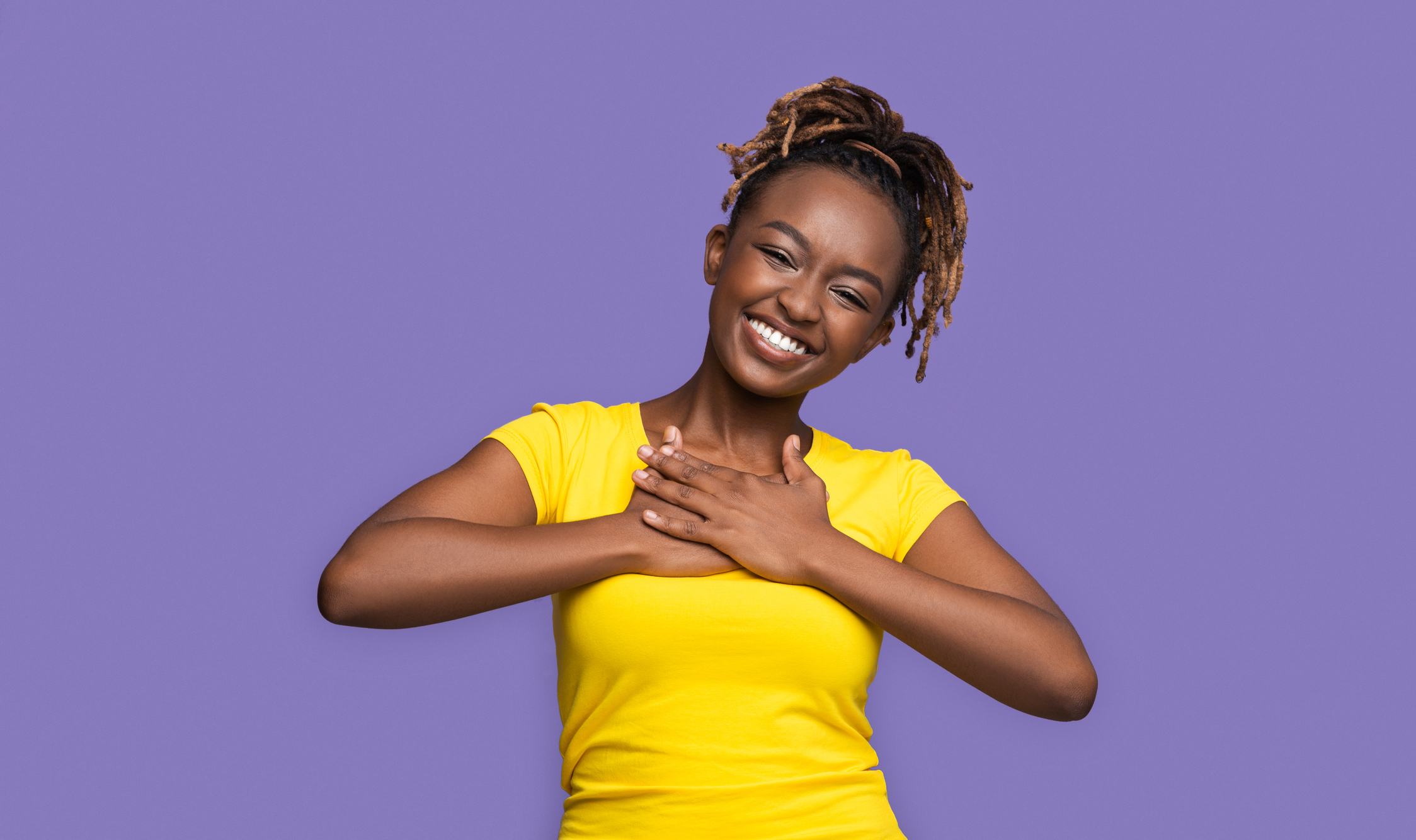 Thankful smiling african girl holding hands on her chest