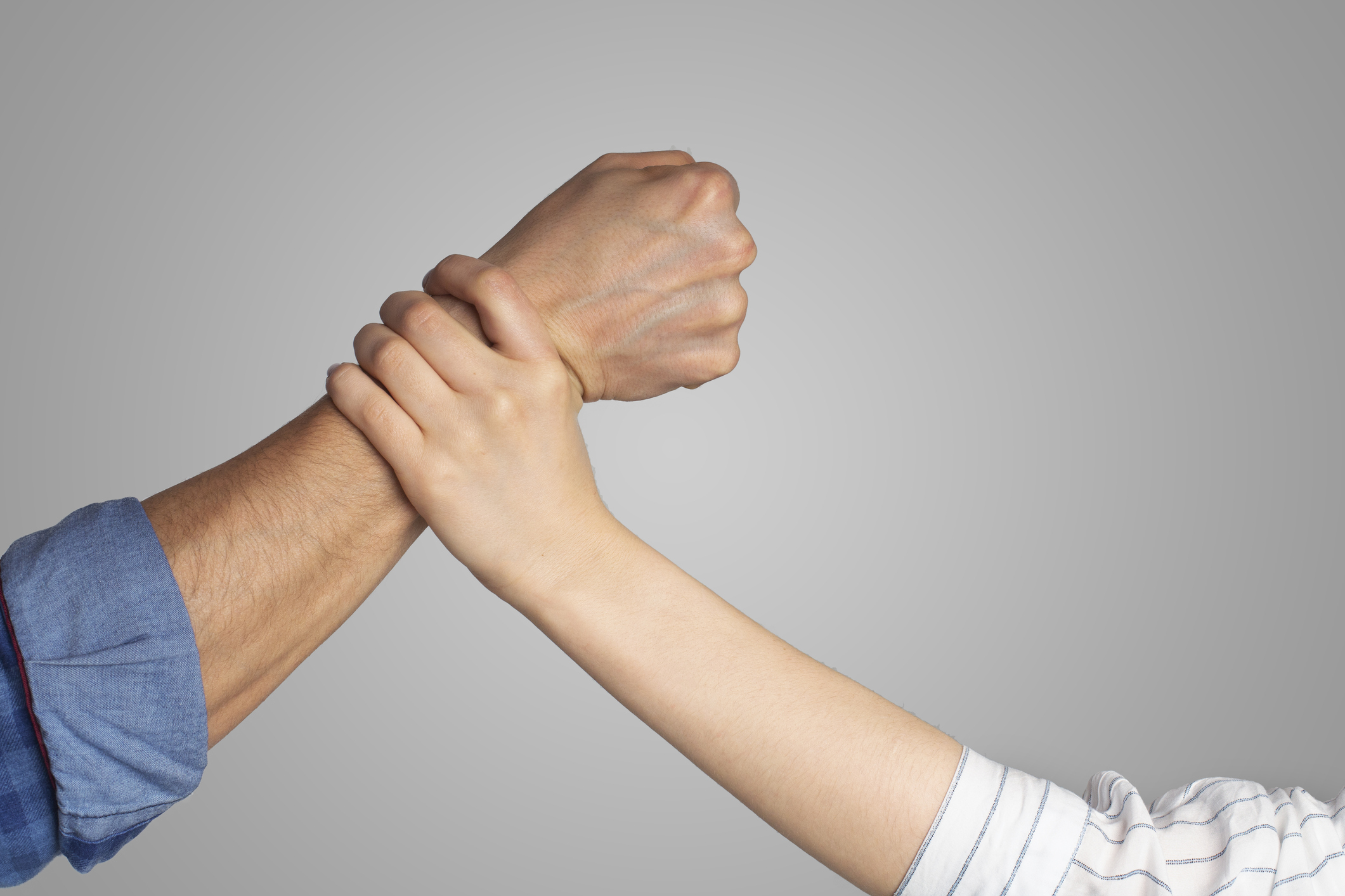 Social problems and protection of women. Male strong fist about to punch lady, woman stops man hand