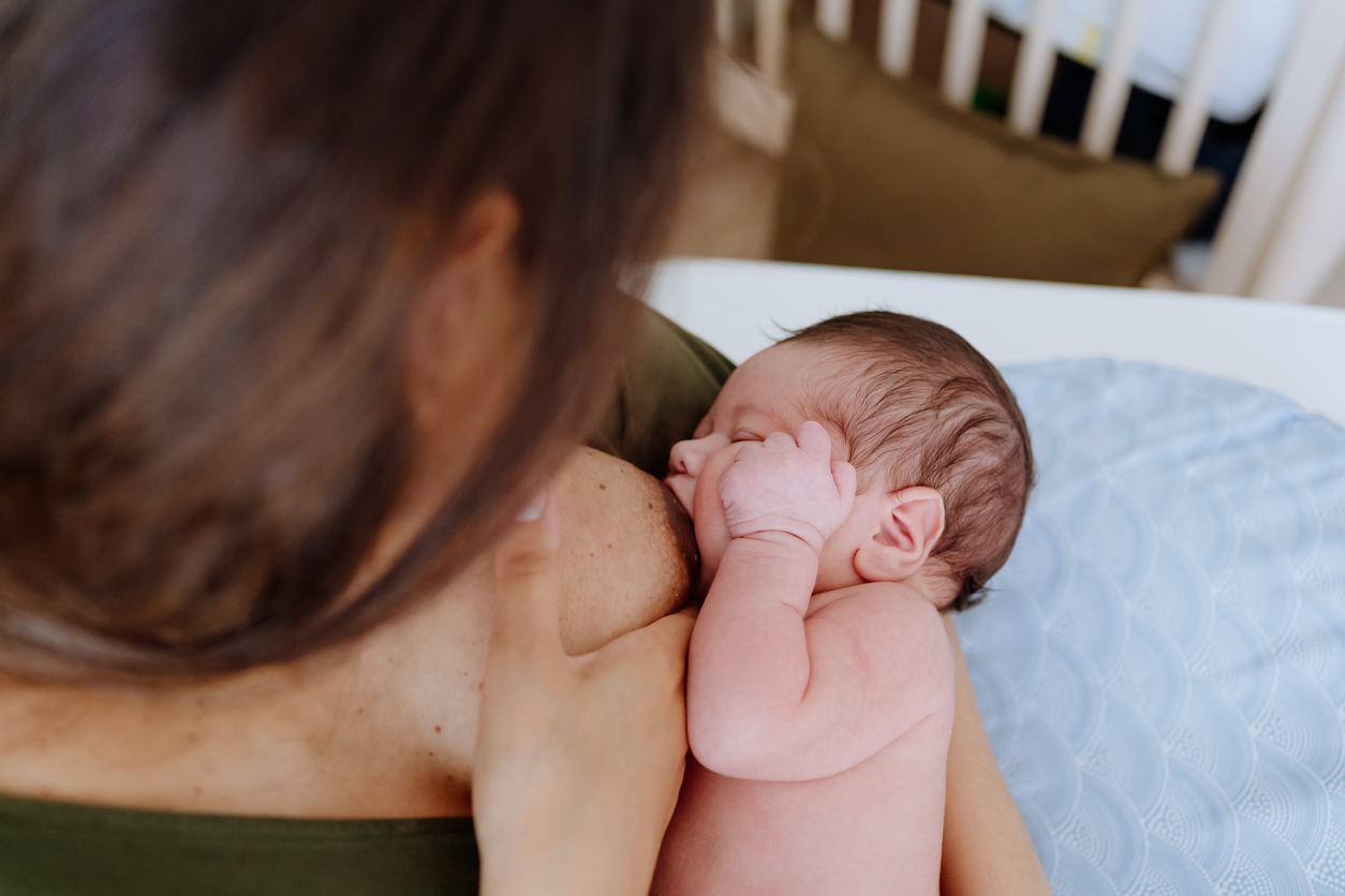 Mother breastfeeding her baby boy in the nursery room