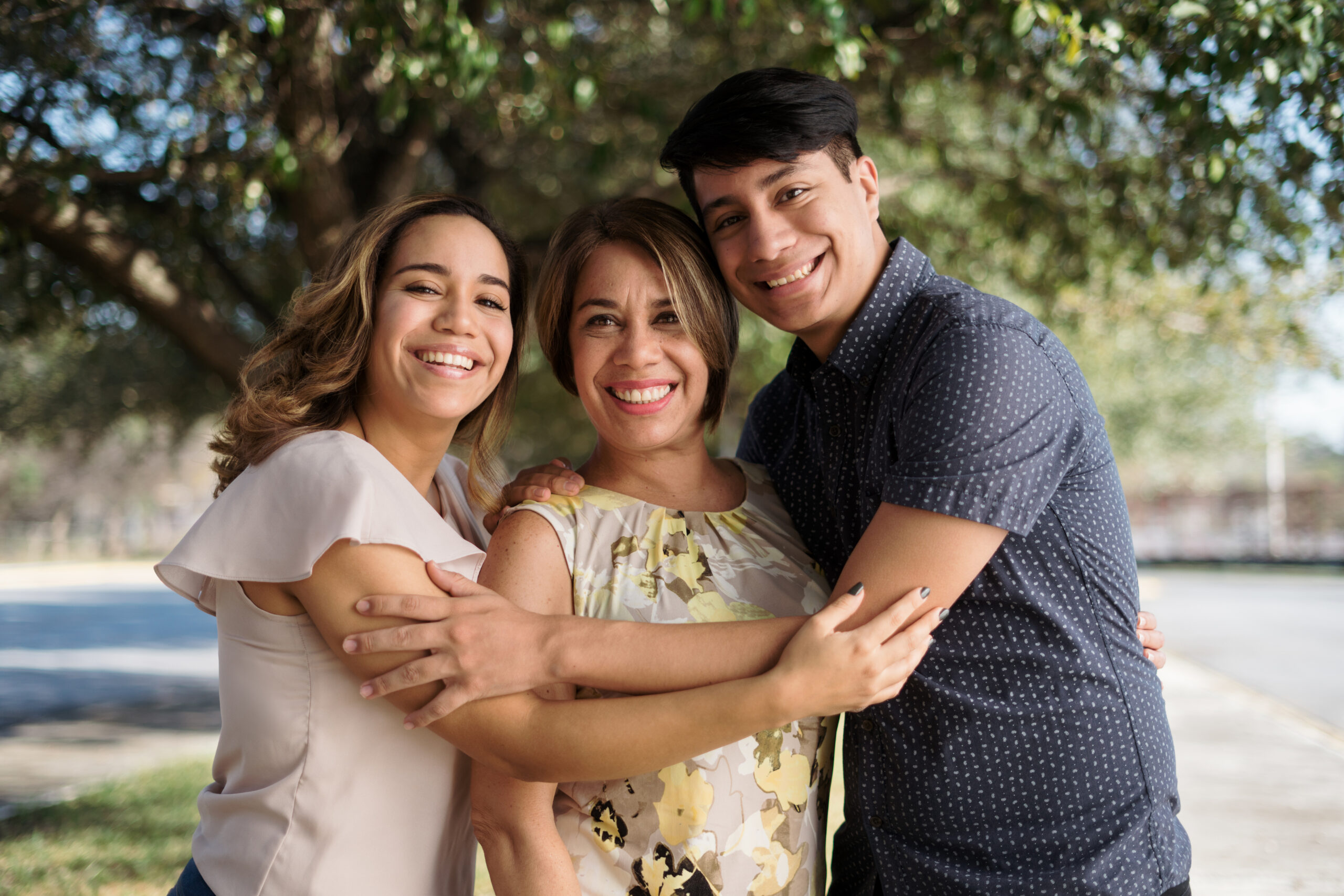 Latin mother with two children standing outside and smiling