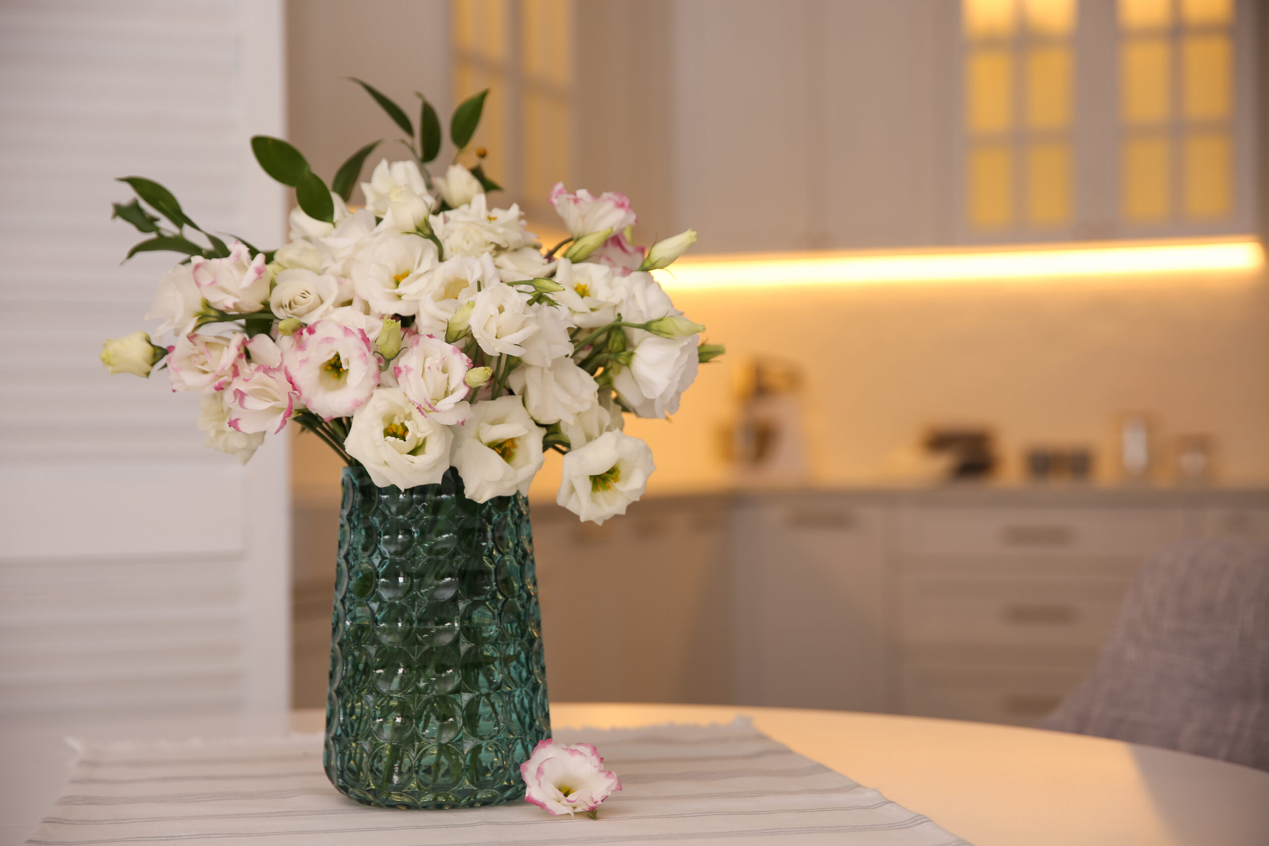 Bouquet of beautiful flowers on table in kitchen, space for text. Interior design