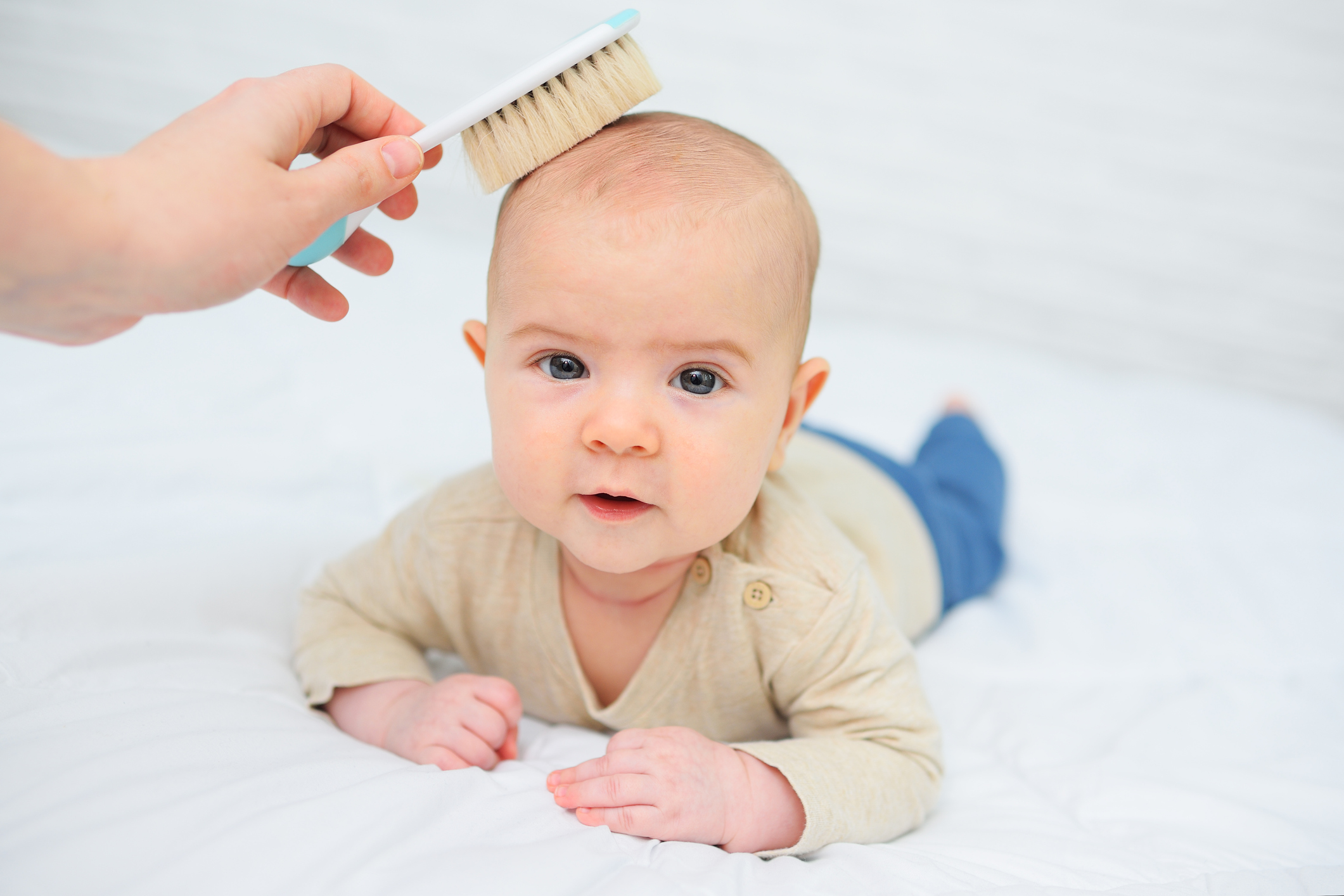 mom combs the baby with a special hair brush on a white background