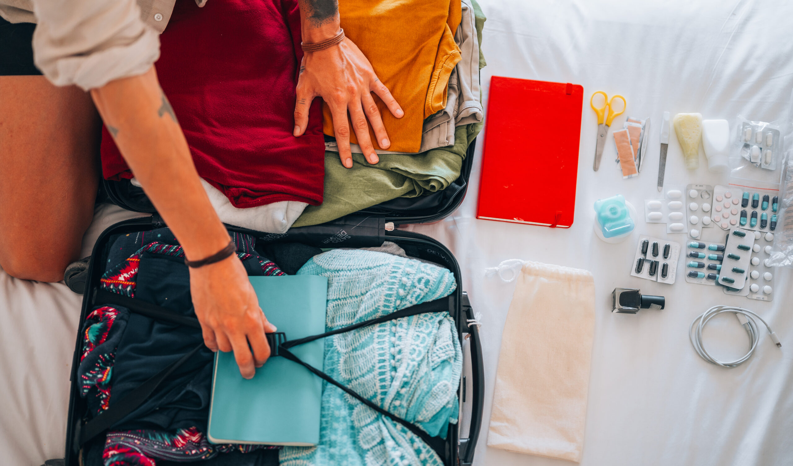 Directly above of man's hand preparing summer luggage